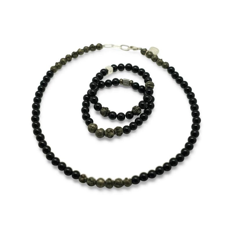 The masculine necklace is comprised of black onyx and carved pyrite skulls. Pyrite is a fiery stone that manifests male energy. It gives one strength and determination needed to face life's challenges. Skulls represent power and immortality. In the