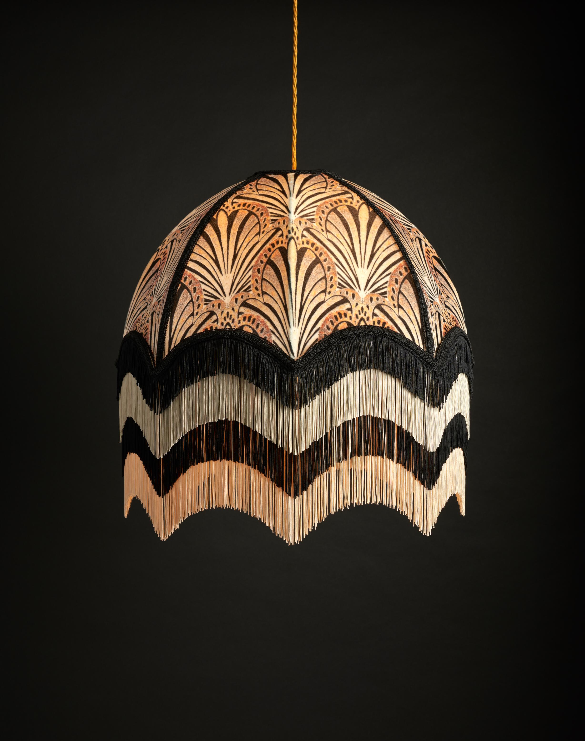 Jada est un magnifique motif en forme d'éventail dans des tons doux d'or et d'ivoire mélangés à du noir. Avec ses quatre couches de franges décadentes, il s'inspire des flappers des années 1920.

Les abat-jour d'Anna Hayman constituent une pièce