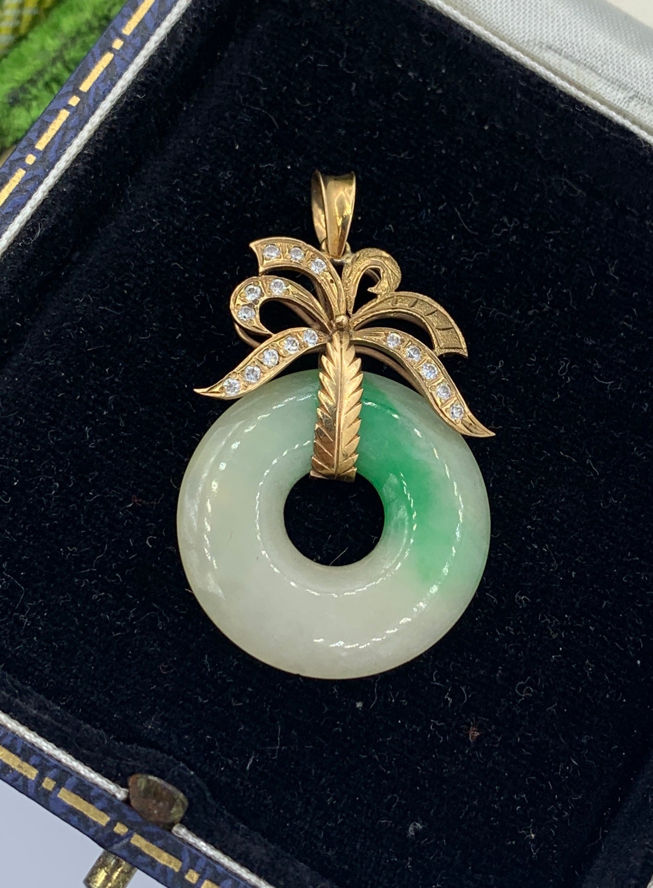 This is a spectacular Antique Jade Diamond Pendant Necklace in 14 Karat Yellow Gold.   The stunning pendant has a round Jade disc with wonderful color variation.  The Jade disc hangs from a surmount in 14 Karat Yellow Gold which is set with 16