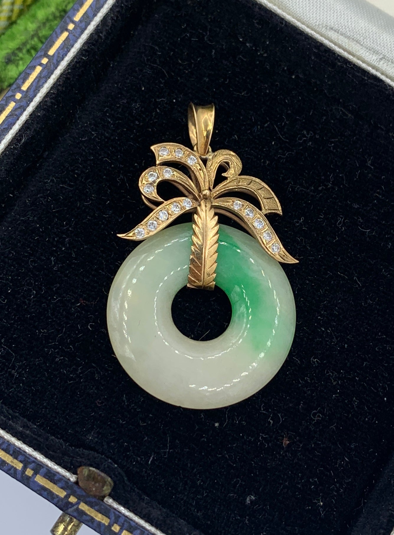 Este es un espectacular Collar Colgante Antiguo de Jade y Diamantes en Oro Amarillo de 14 Kilates.   El impresionante colgante tiene un disco redondo de Jade con una maravillosa variación de color.  El disco de jade cuelga de una montura de oro