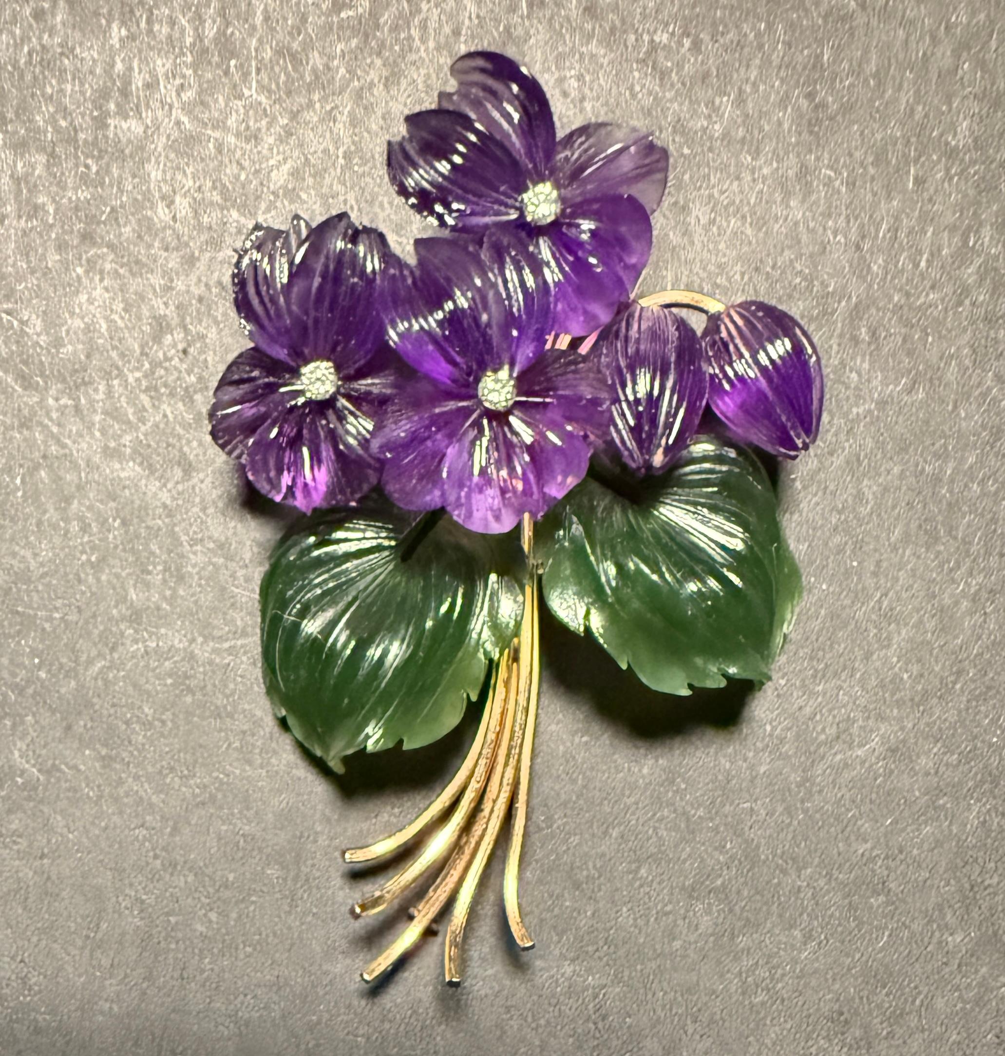 14k yellow gold brooch in the form of a floral grouping. Set with amethyst flowers, jade leaves and single cut diamonds. 
Marked 585 with makers mark.
Weight 21.2g
