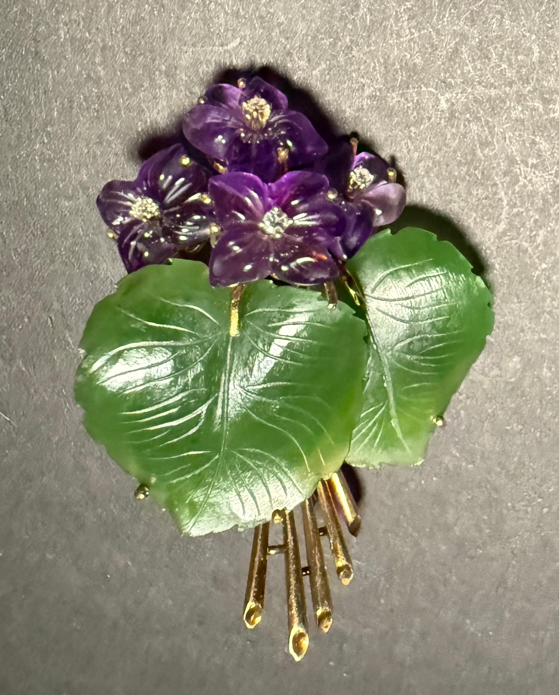 14k yellow gold brooch in the form of a floral grouping. Set with amethyst flowers, jade leaves and single cut diamonds.  Marked 585 with makers mark. 
Weight 16.4g.