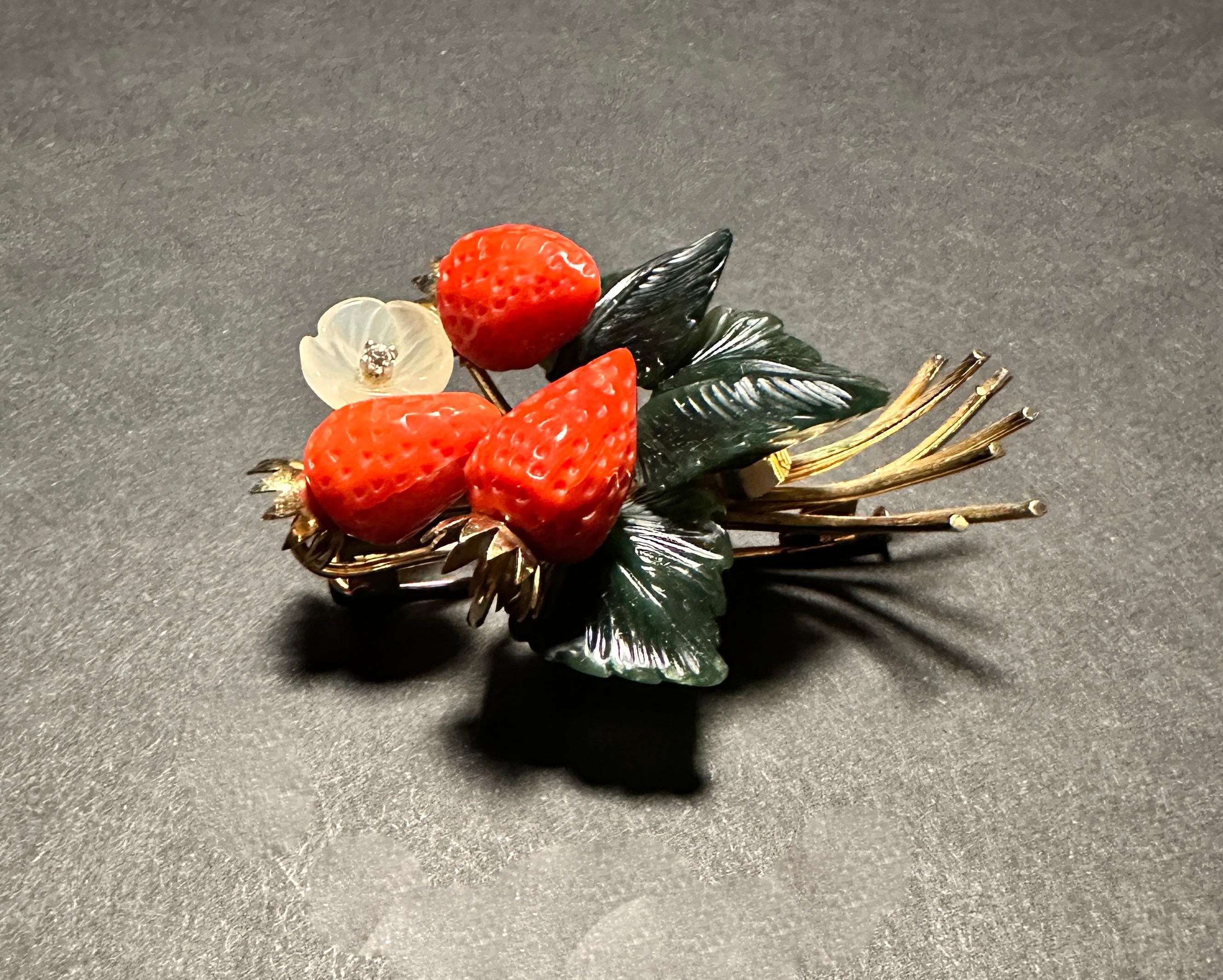 This vintage brooch represents a branch of a strawberry plant with engraved jade leaves. The vines are from 14k yellow gold and the strawberries are of carved coral. Carved crystal flower.
Marked 585 with makers mark.