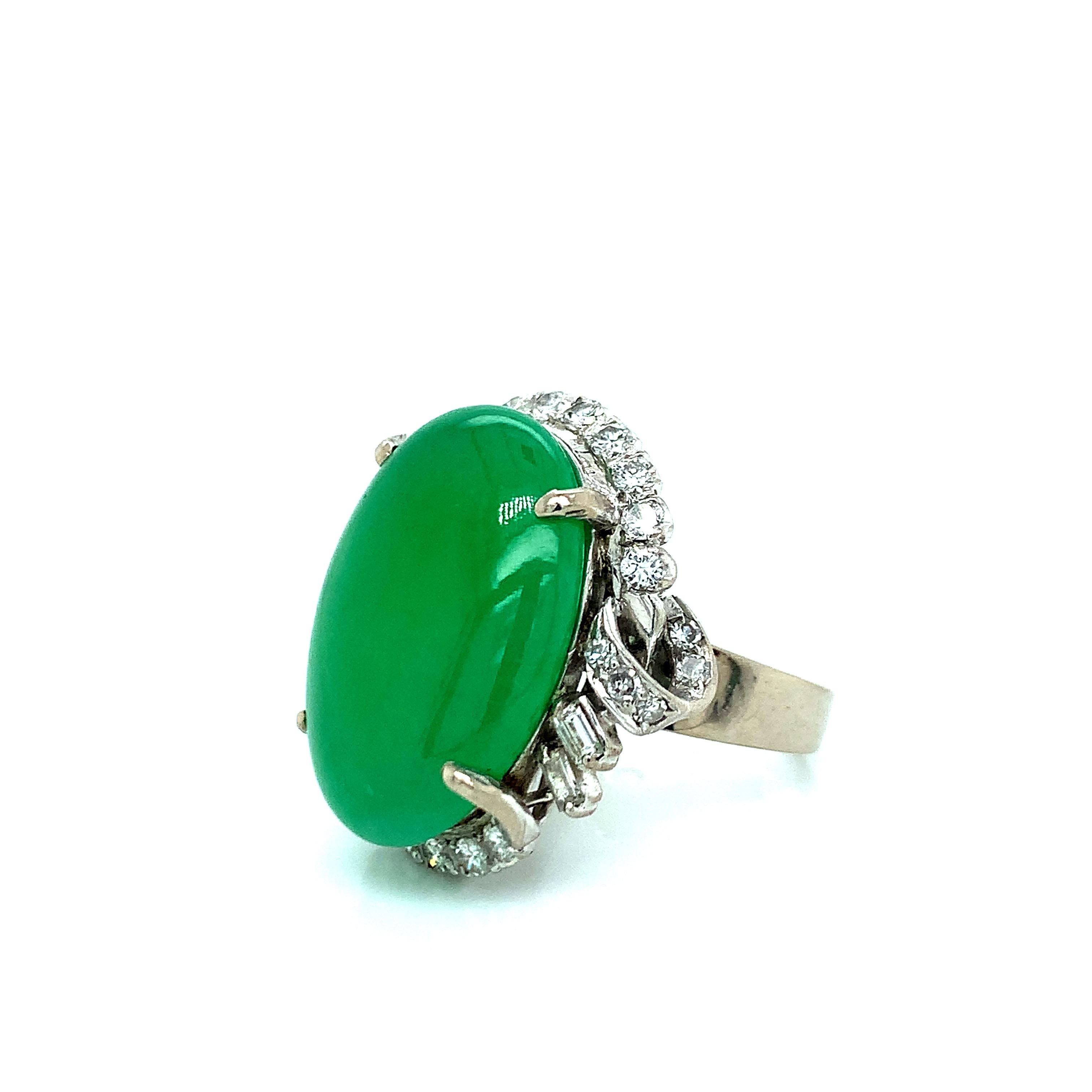 A 14 karat white gold ring that features one cabochon apple green jade gauged at 22.0 mm x 16.32 mm at its center. It is accented by a halo of thirty round full-cut and baguette-cut diamonds, totaling approximately 1.00 carat (graded H-I color and