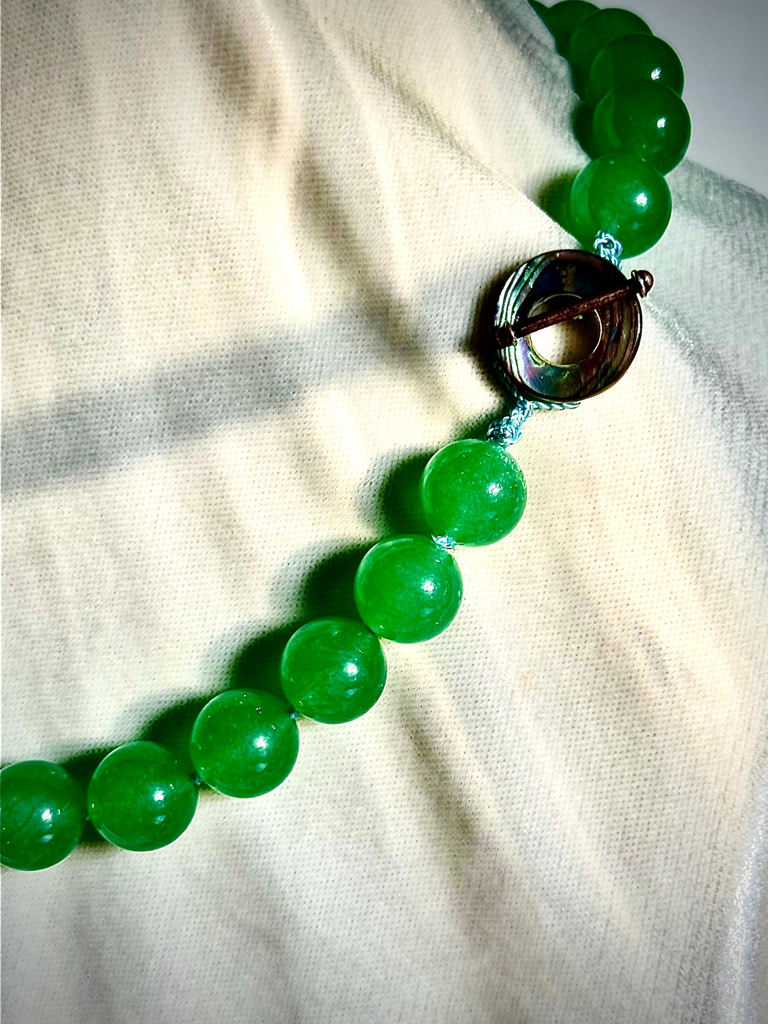 Very chic single strand necklace of luminous green jade beads and very lustrous coin pearls. 

The strand is of 14mm round light green jade beads. Separating stations of three beads are four fresh water cultured 12mm coin pearls. These pearls have a