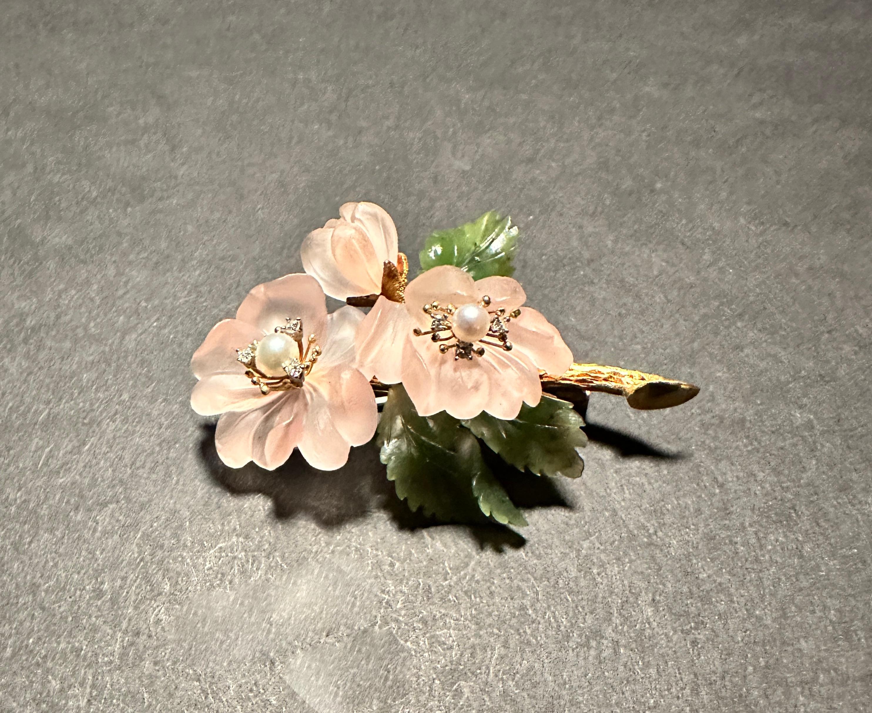 Jade and rose quartz 18K yellow gold floral form  brooch pin. Pearls and diamonds with carved rose quartz pedals and jade leaves.
The delicate blossom of this brooch is crafted from rose quartz, Three leaves, fashioned from deep green jade The