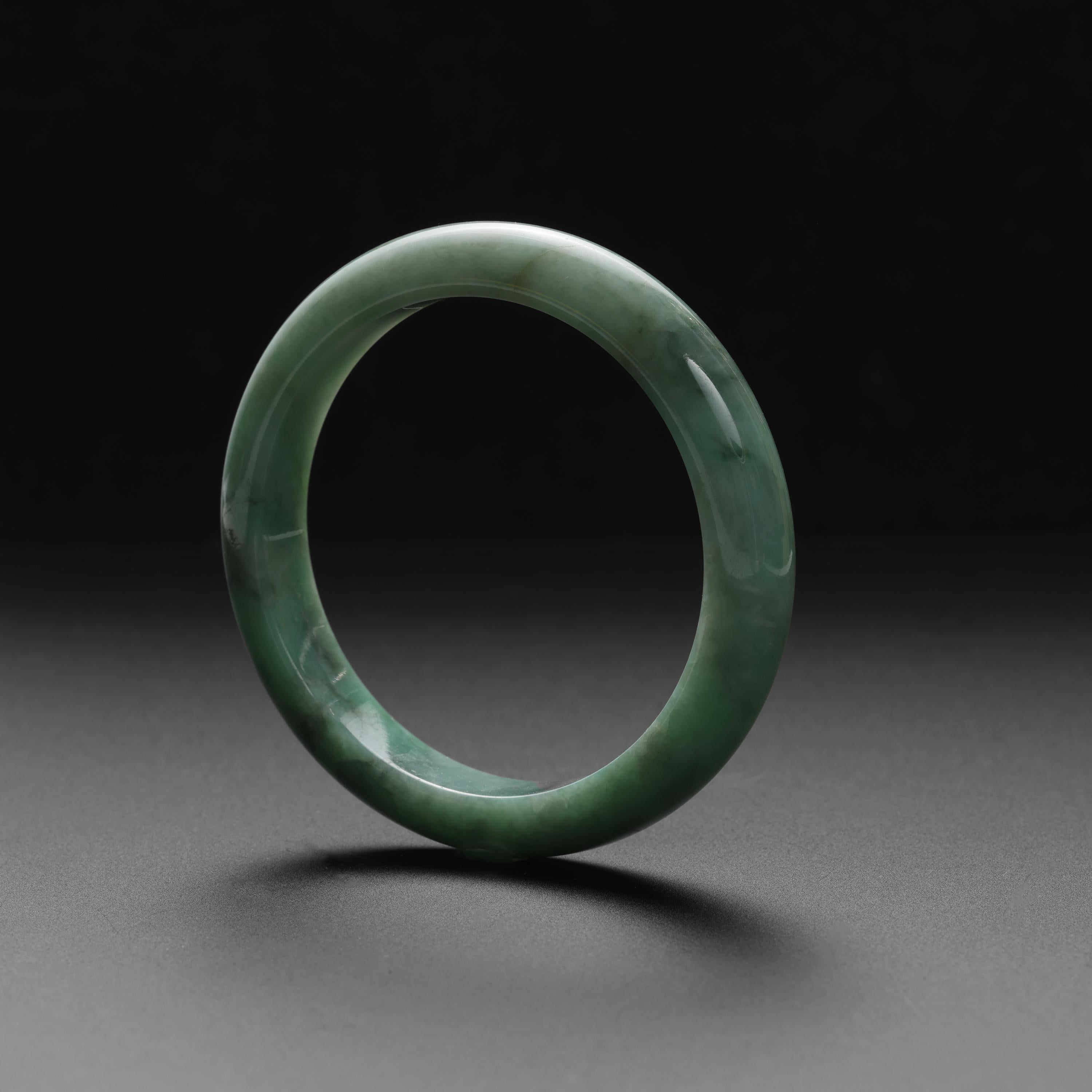 This gleaming certified natural and untreated Burmese jadeite jade bangle has an inner diameter of 55.4mm. The bangle is a mottled light apple green color and displays beautiful grain. The 