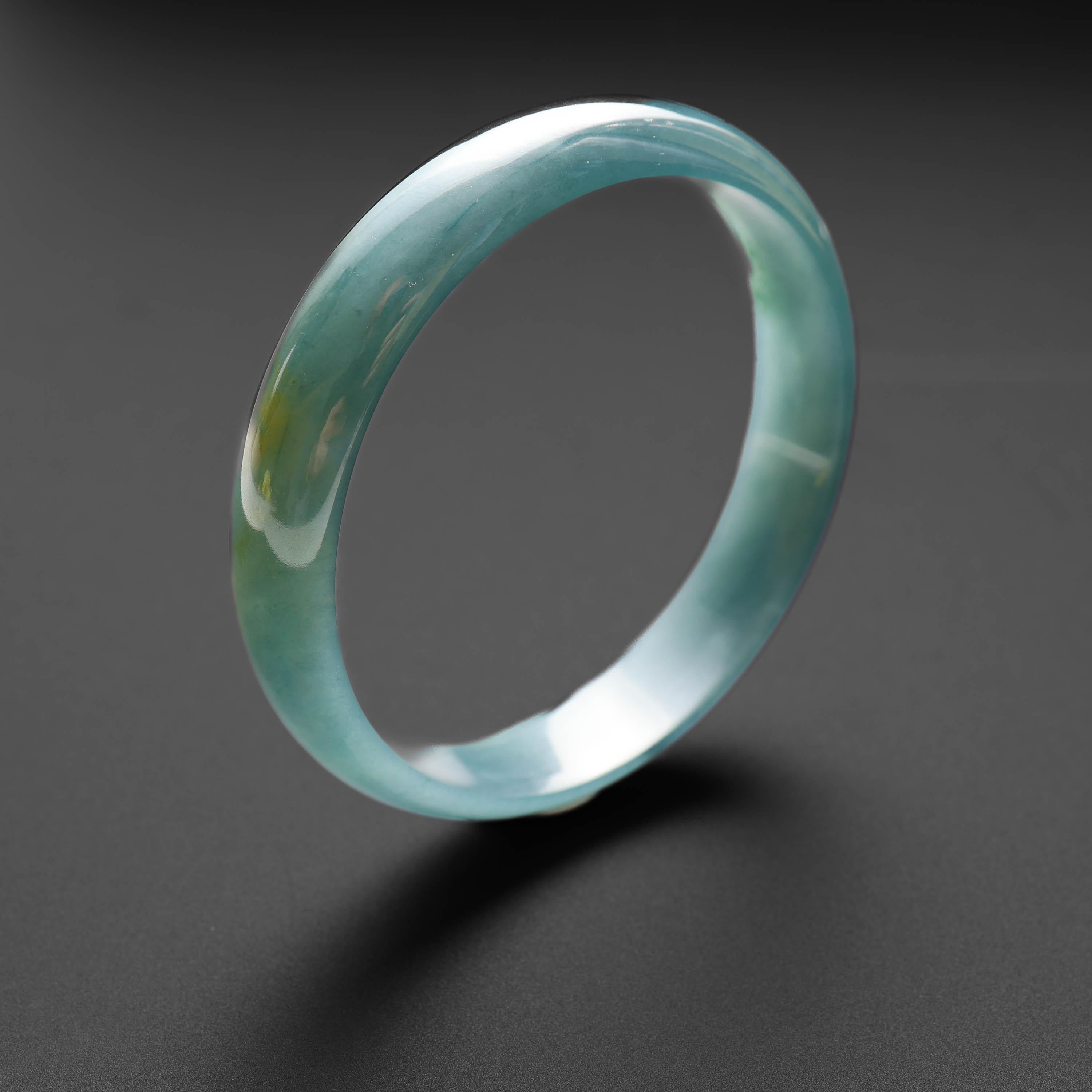 This hand-carved half-round jade bangle was created from translucent bluish-green untreated jadeite. It has an inner diameter of 57mm, so it will fit a small to average-sized wrist. Incredibly translucent and luminous, jadeite jade bangle is simply