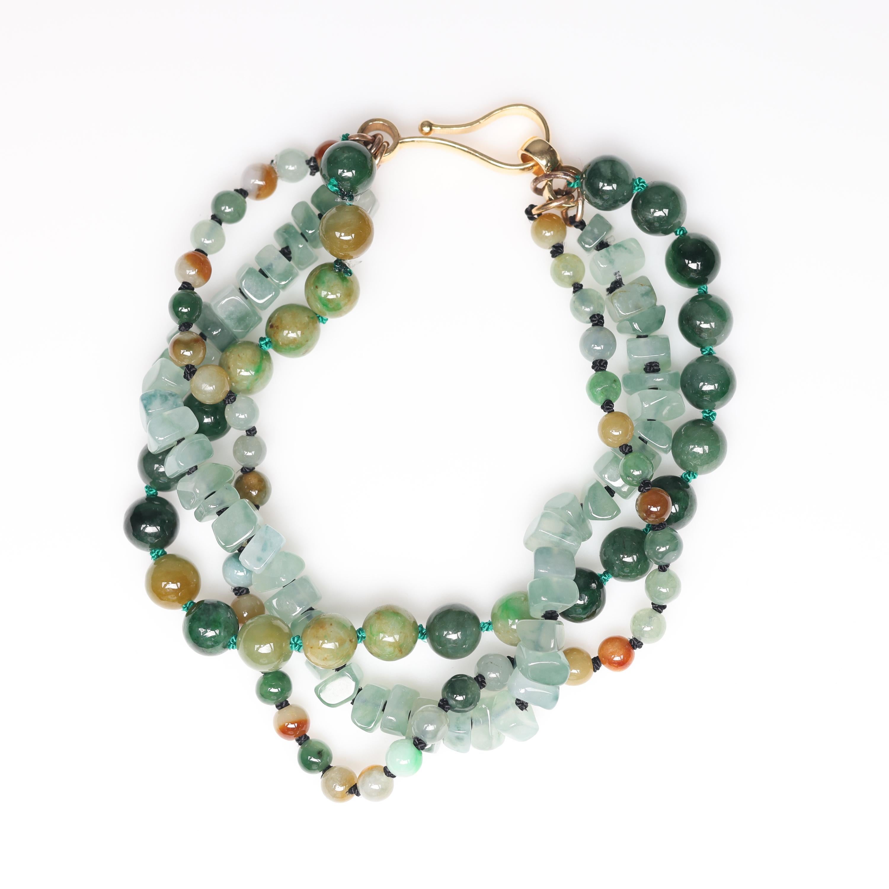 This brand new beaded jade bracelet features both jadeite jade and omphacite jade beads. The three strands of beads are strung on silk and knotted between each bead. One strand contains freeform jade beads and the other two feature round beads that