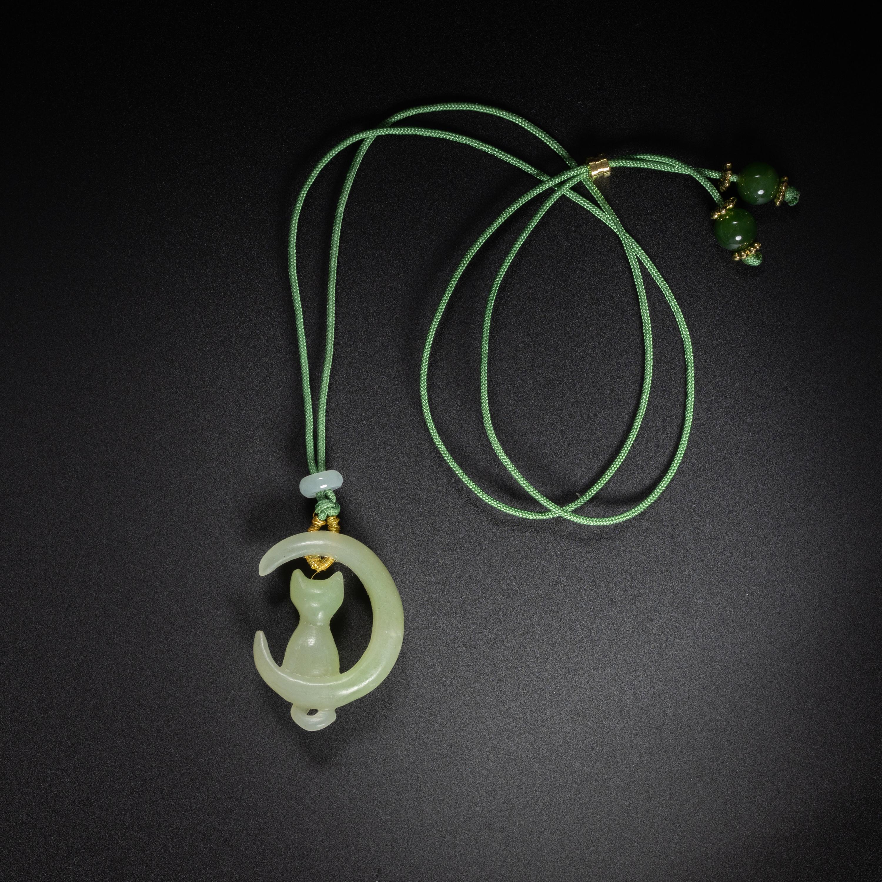 Hand-carved from natural, untreated nephrite jade, this charming cat is perched within a crescent moon. The carving is sensitive and expressive; the pendant one-of-a-kind. A sturdy black nylon cord transforms the carving into a necklace. Ships with