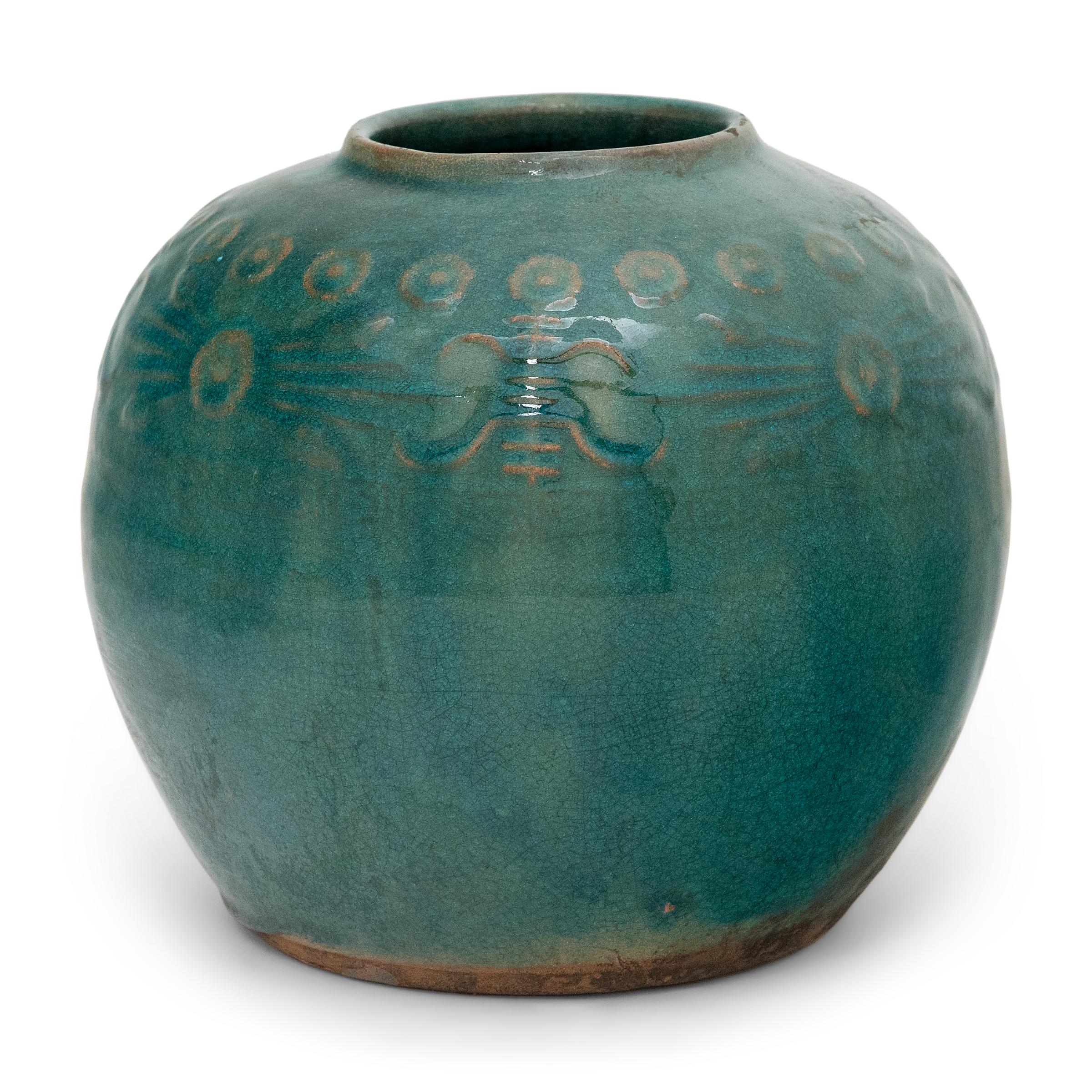 A glassy, blue-green glaze gracefully drips across the rounded body of this provincial kitchen pot, lingering beautifully on the low relief decoration to the jar's shoulders. Among the raised patterns are round chrysanthemum blossoms and stylized