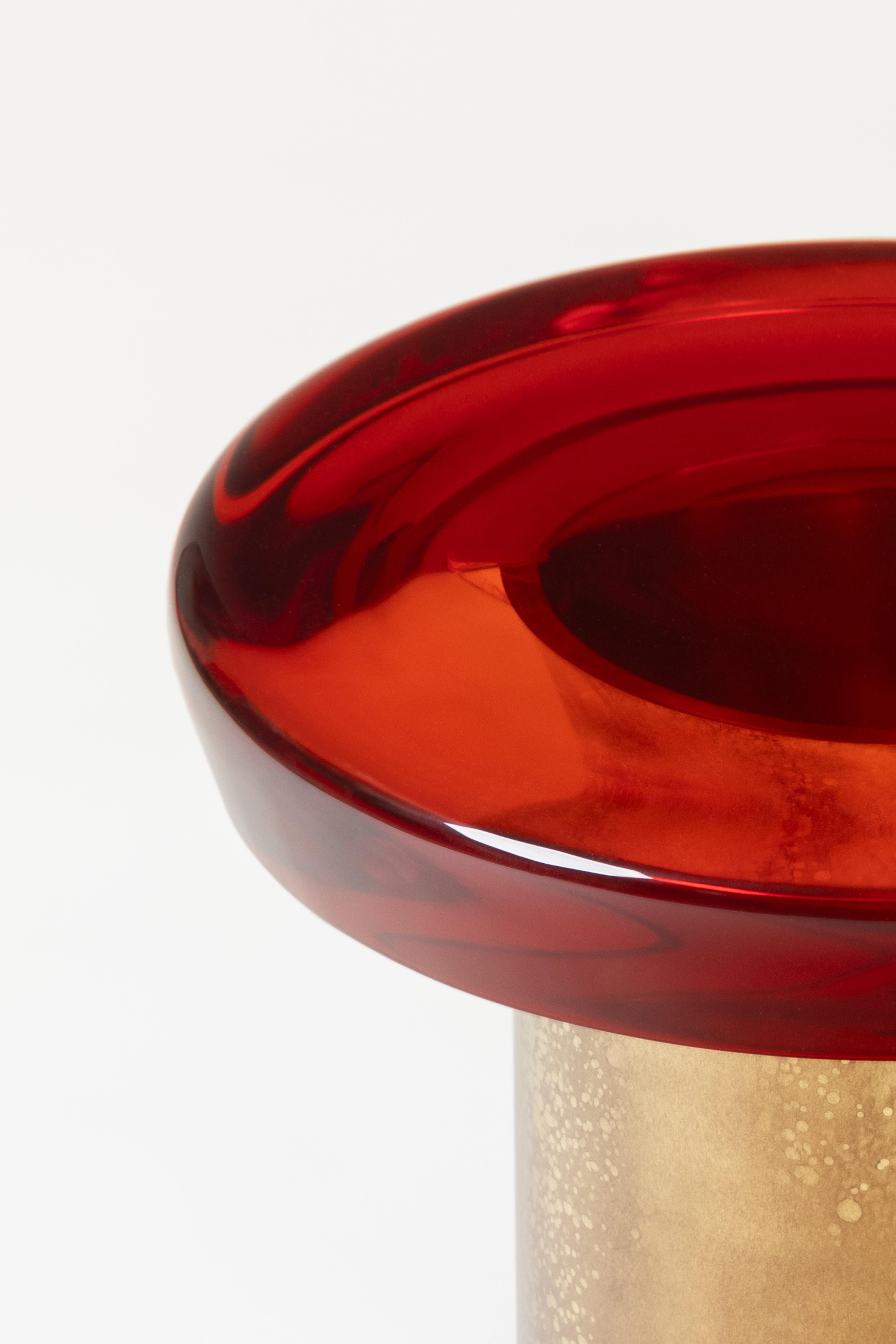 La table basse Jade se caractérise par une transparence éthérée et une surface réfléchissante qui joue naturellement avec la lumière. Le plateau de table aux couleurs vives repose sur une base cylindrique en laiton, dont les veines distinctives sont