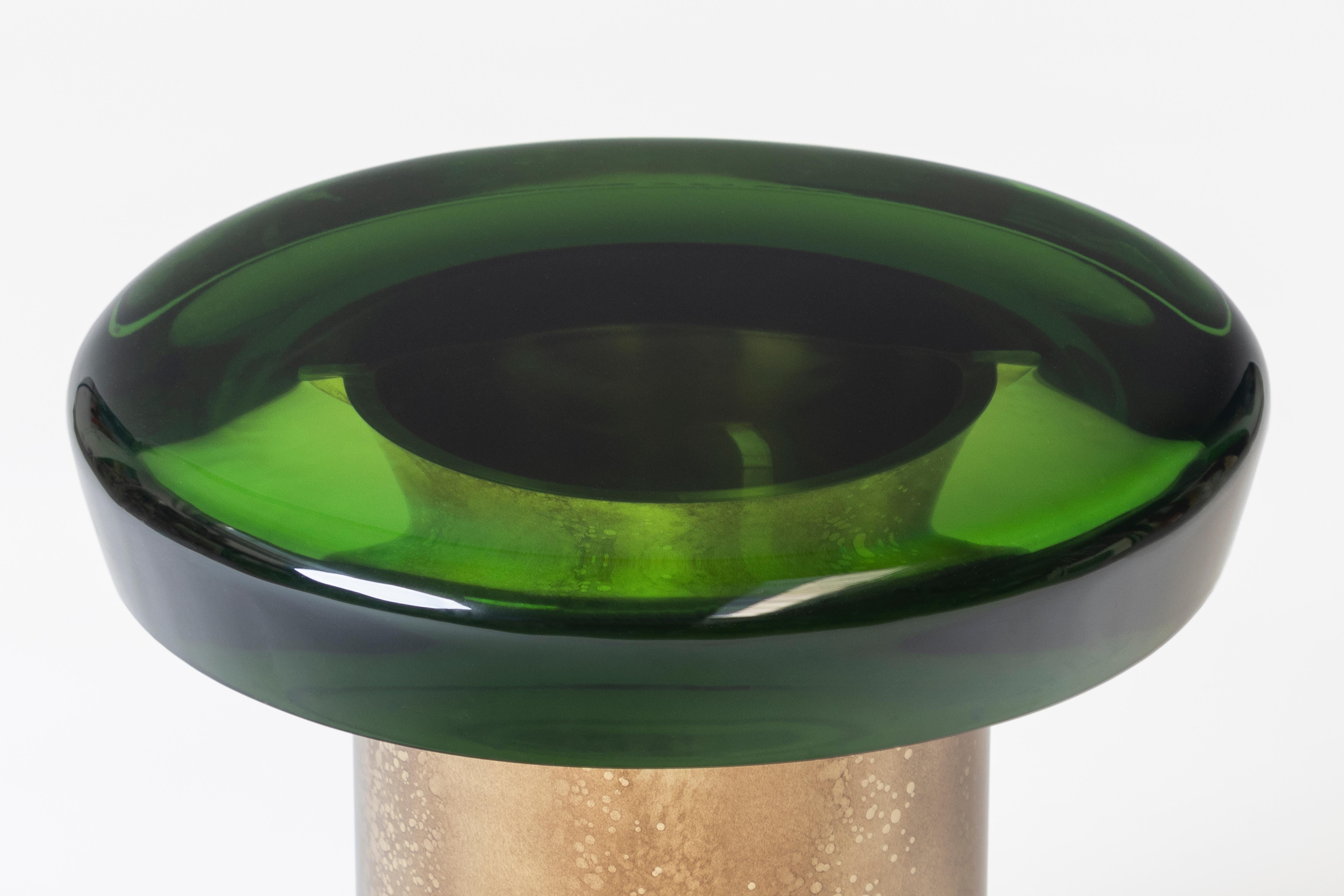 Jade coffee table features ethereal transparency and a reflective surface that plays naturally with light. The brightly colored table top rests on a cylindrical brass base, whose distinctive veining is achieved through a skillful etching treatment.