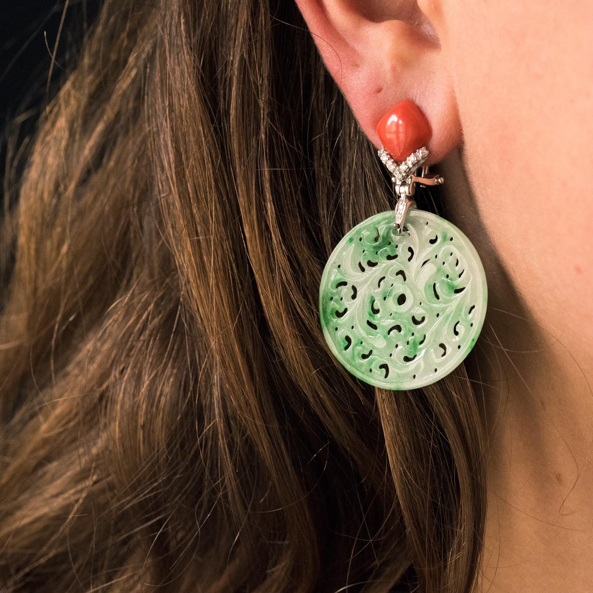 For pierced ears.
Pair of 18 karats white gold earrings.
Each pendant earring is set with a cushion cabochon coral, supported by a V set with diamonds, the base of which holds an engraved and perforated jade disc. The hanging system is a peak with