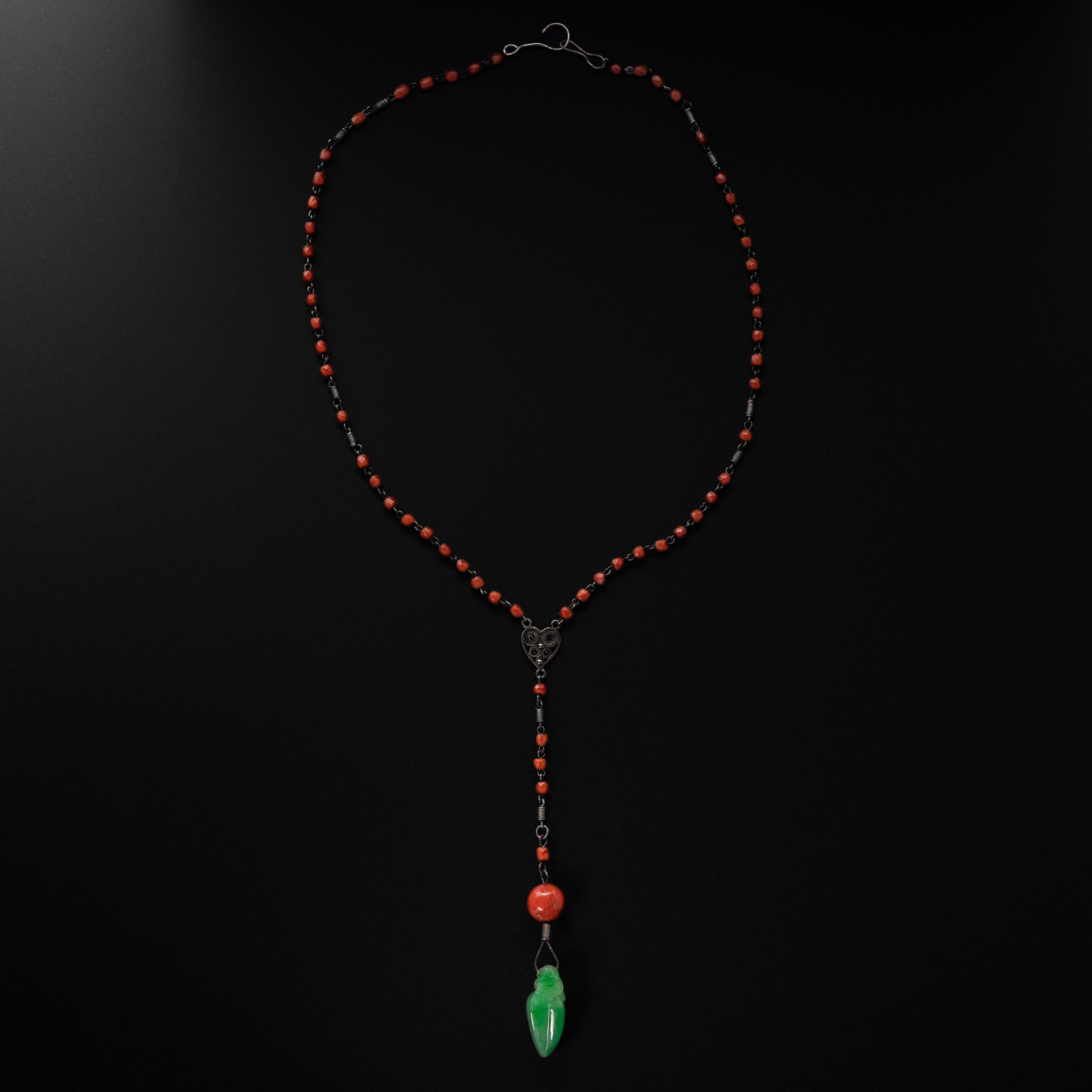 This 1930s-era Art Deco necklace features a gorgeous apple green natural Burmese jadeite carved into the form of a star fruit. The 27.40mm x 11.71mm x 11.58mm translucent jade carving is suspended on a silver nail and connected to a large (11mm)