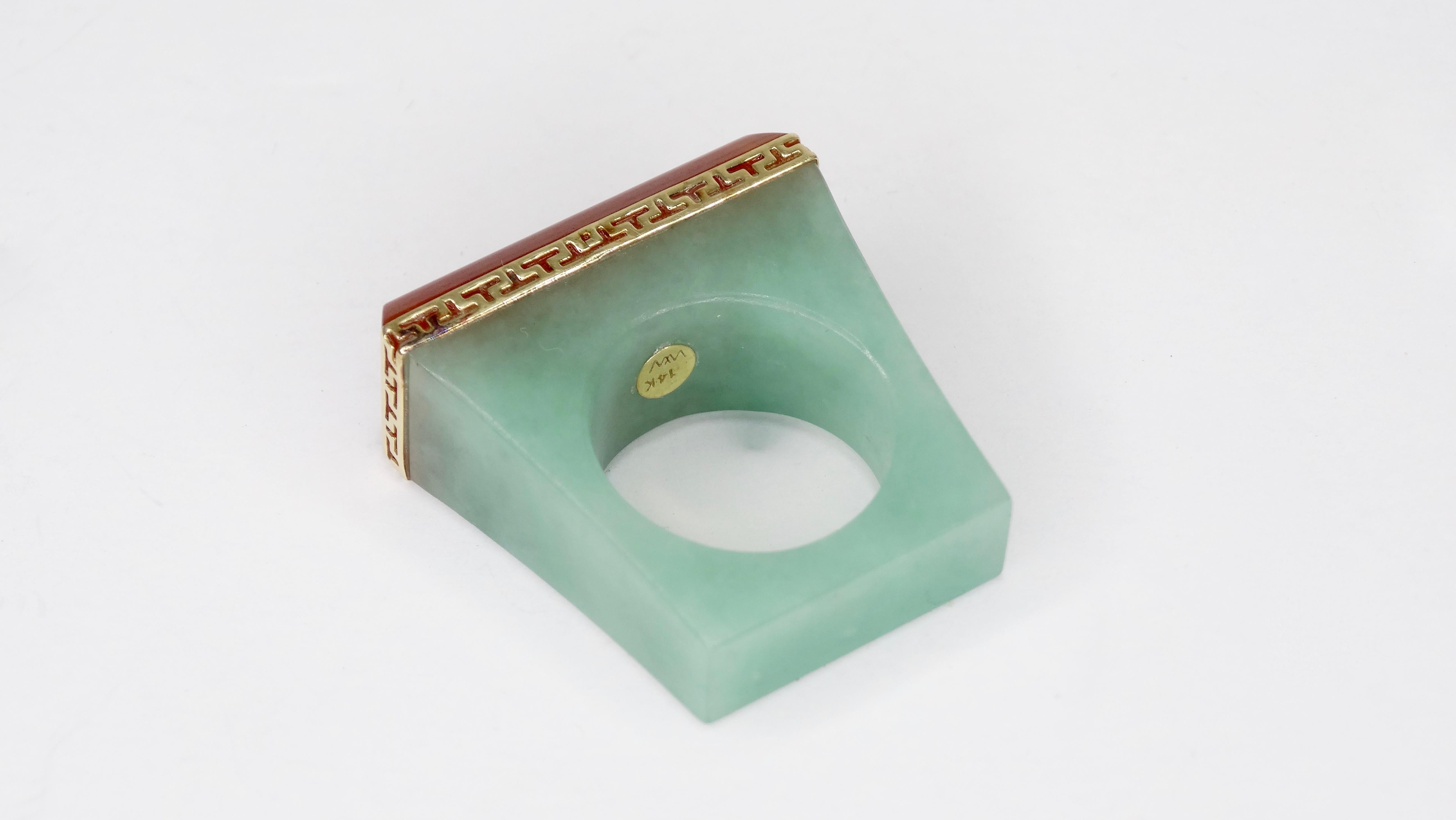 Circa 1980s, this stunning Jade cocktail ring features a rectangular shape and is crafted from Cornelian and Jade. Framing the baguette cut Cornelian is a decorative 14k gold trim. Interior of ring is stamped 14k Gold, WW. Ring is a size 6 and
