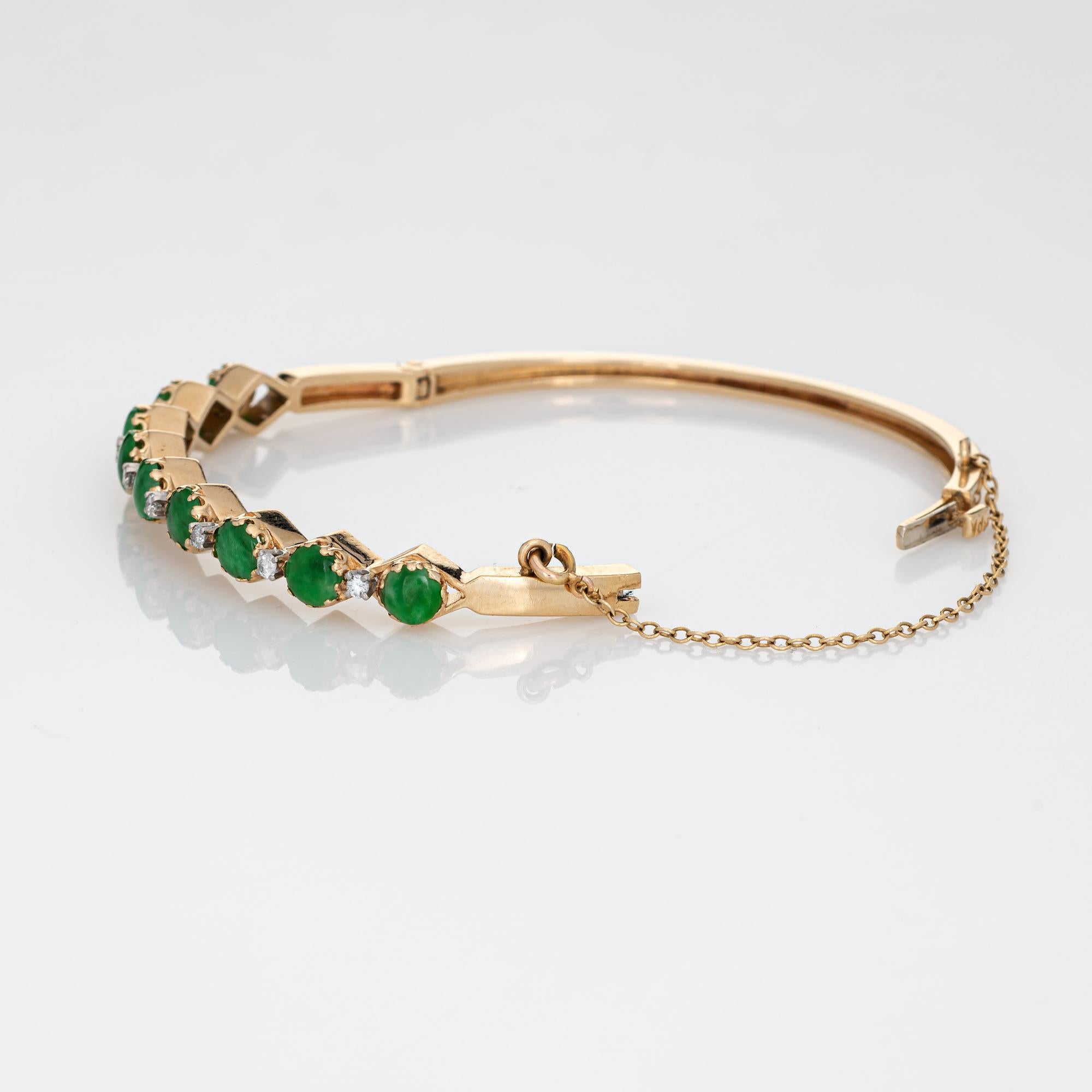 Stylish and finely detailed vintage jade & diamond bangle bracelet crafted in 14 karat yellow gold (circa 1970s to 1980s). 

Nine cabochon cut pieces of jade measure 5mm each. A total of 8 diamonds are estimated at 0.03 carats each (0.24 carats