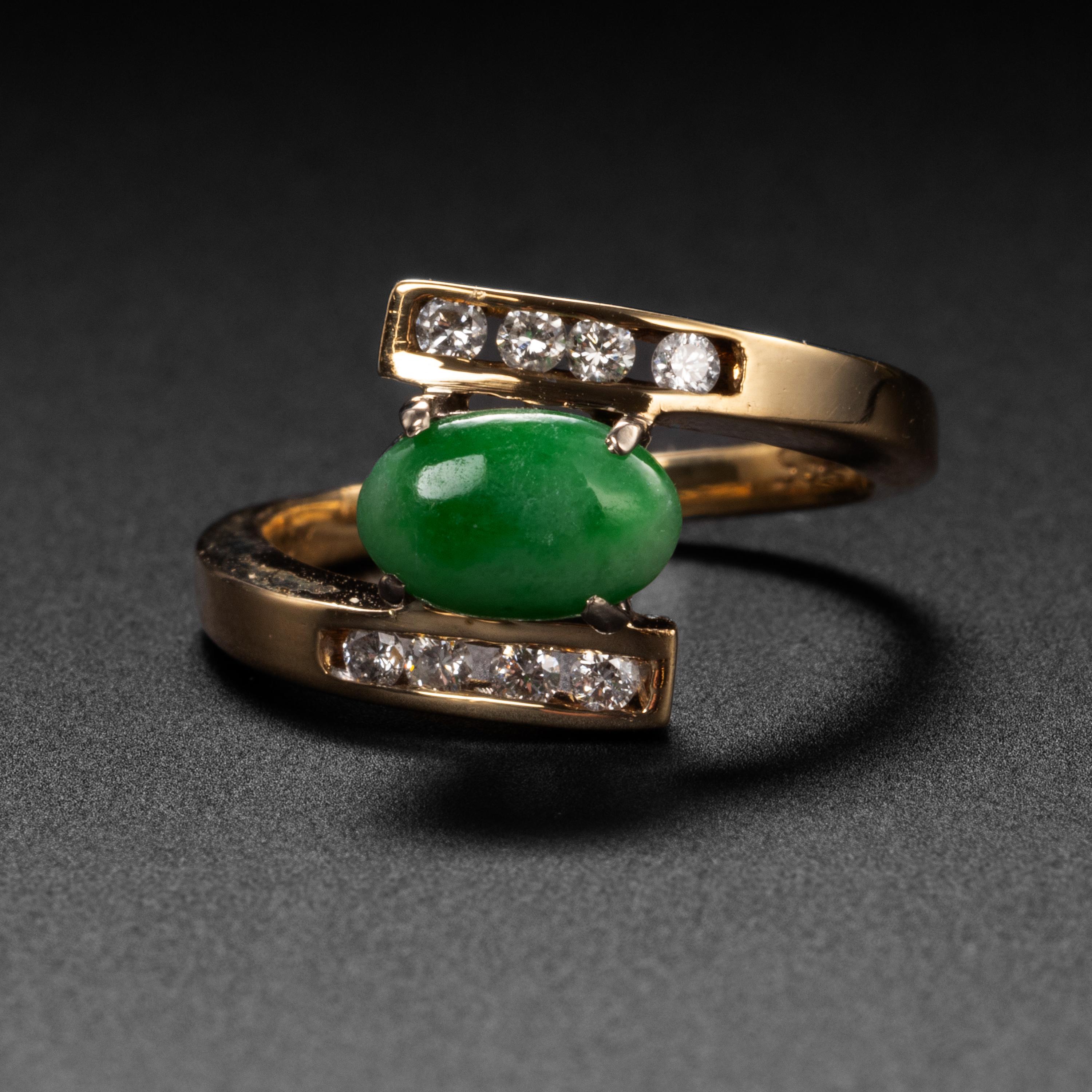 This 1970s-era bypass ring features a central oval cabochon of green jadeite jade, prong-set between the two ends of the 14K yellow gold band. Four .02 carat diamonds are channel-set within the end of the band, adding just a touch of sparkle.

The