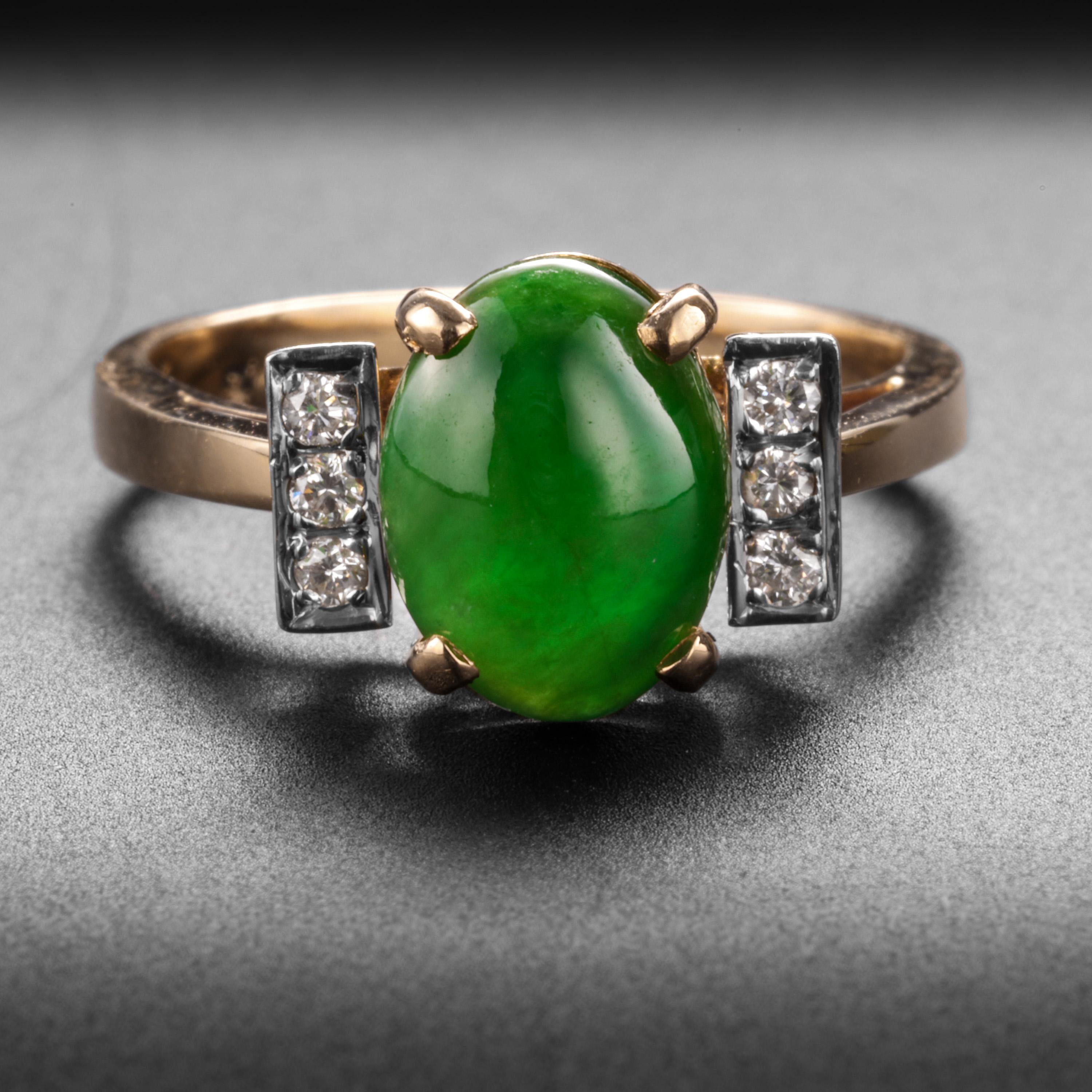 This sweet and beautiful 14K yellow gold engagement ring features a prong-set emerald-green double-cabochon of natural, untreated jadeite jade. The gorgeous stone measures 9.54 x 7.21 x 3.43mm. Three sparkly little .02-carat diamonds are set within