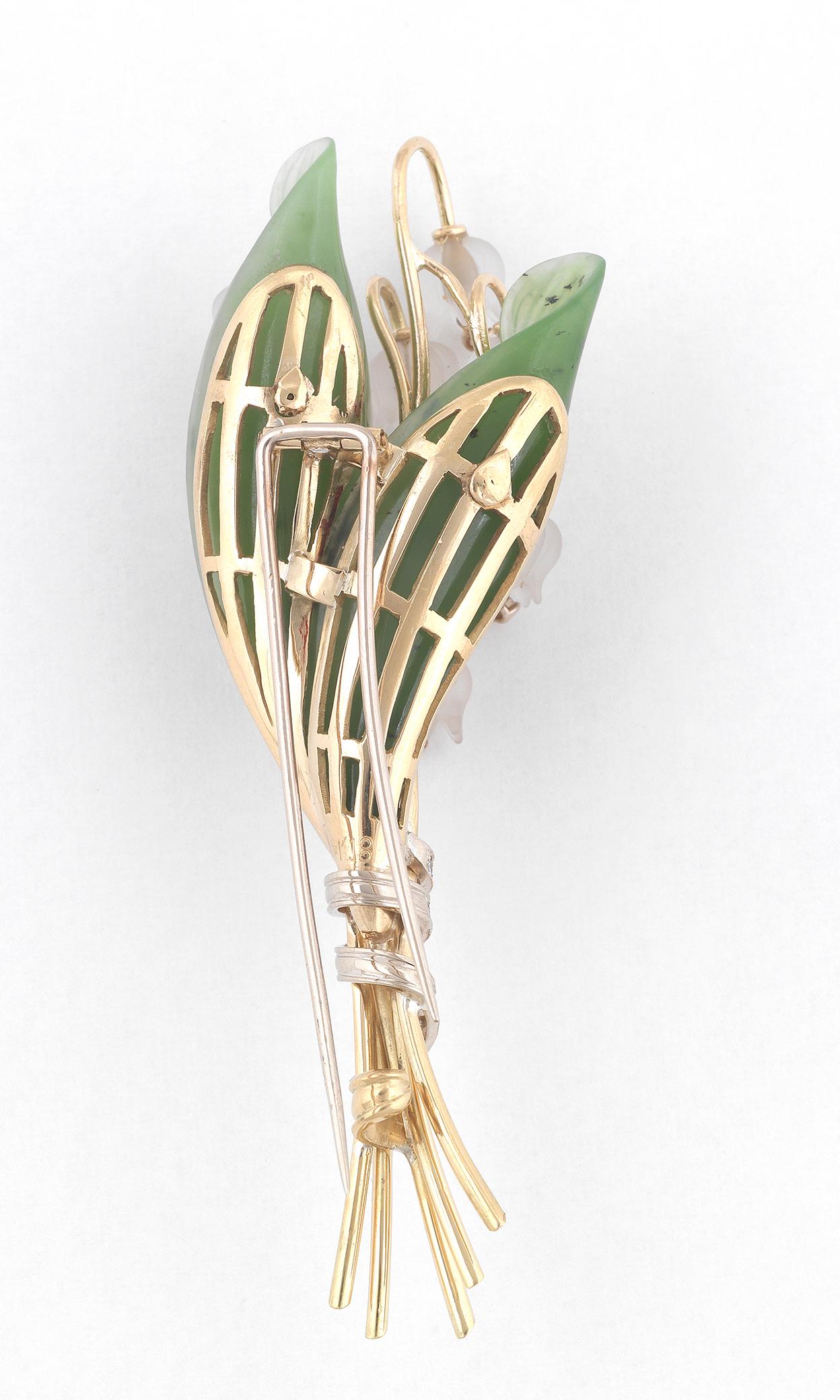 The brooch realistically modeled as a stalk of lily of the valley, set with carved moonstone flowers each suspending a  diamond, to a couple of carved jade leaves, the stems accented by 3 lines of diamonds.
Mounted in 18Kt gold
Length: 9 cm
Weight: