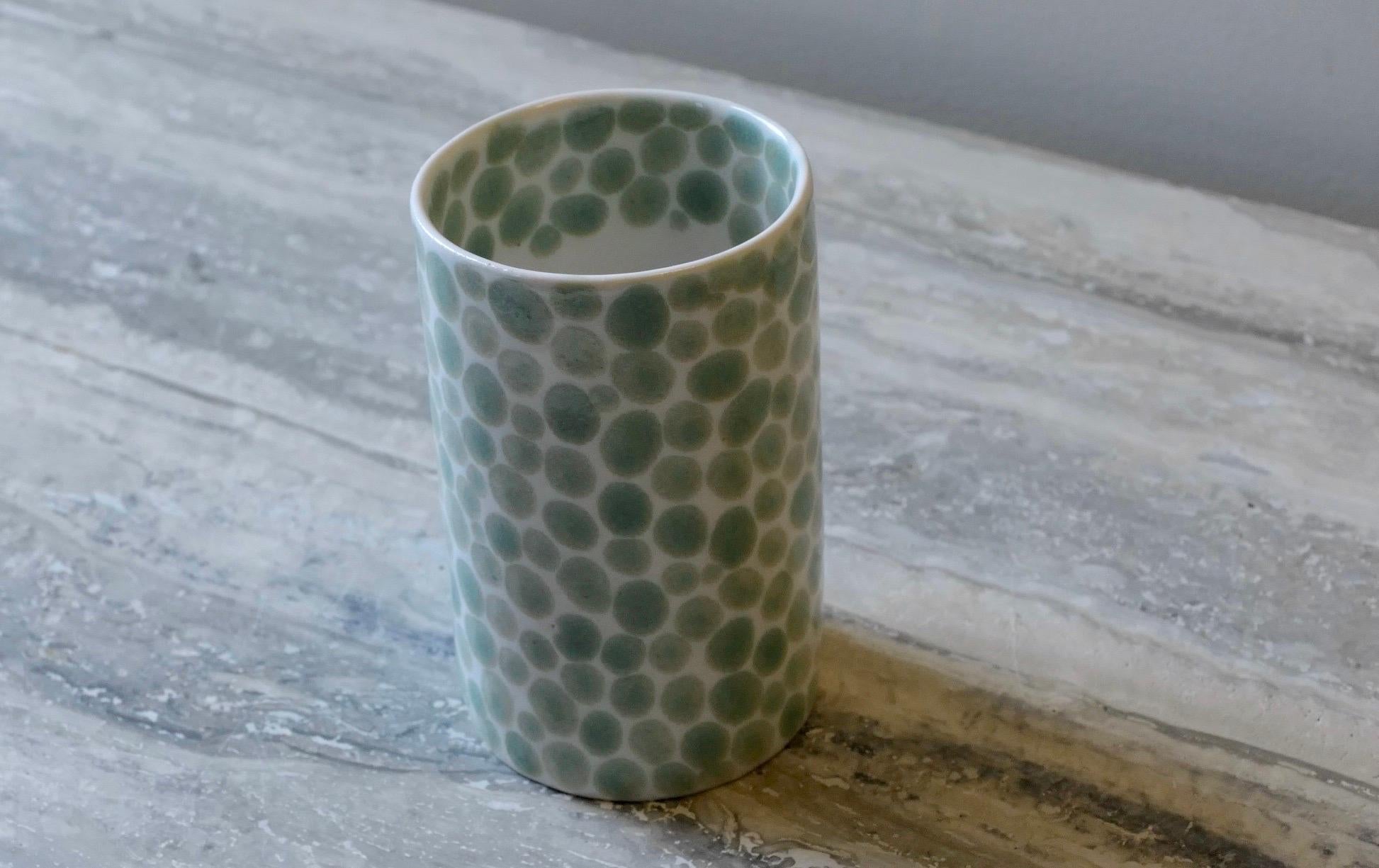 This porcelain cup is slip casted from liquid porcelain and individually painted in light green dots. The glaze is luminous and the cup walls are thin so light goes through. Perfect size for a morning latte or green tea. Tall and elegant shape.