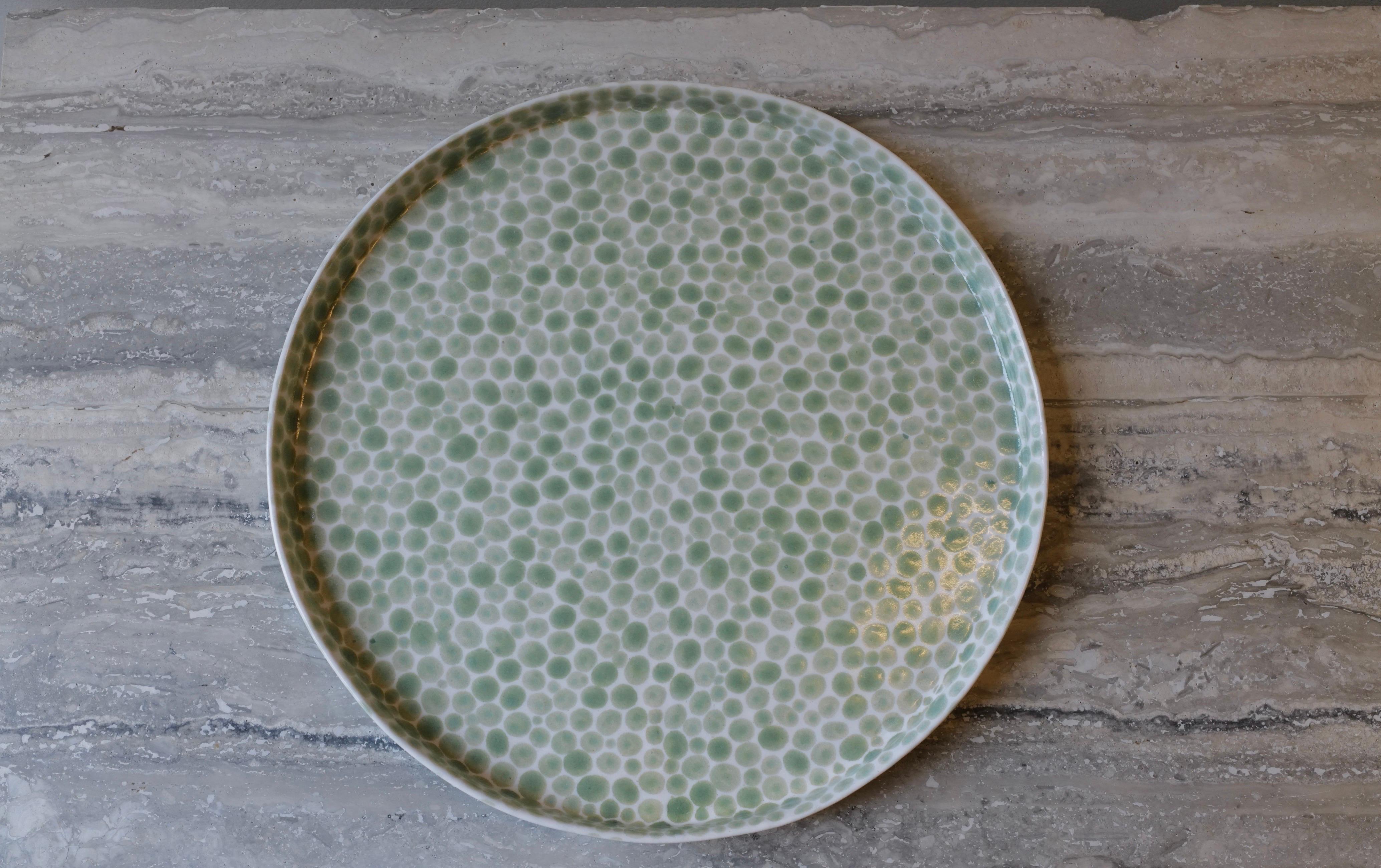 Large ceramic tray or serving platter. Hand-cast in porcelain and once bisque fired, each dot is hand-painted with a jade glaze. An unconventional layered glazing technique, developed by the artist, is used in these cast porcelain pieces. The