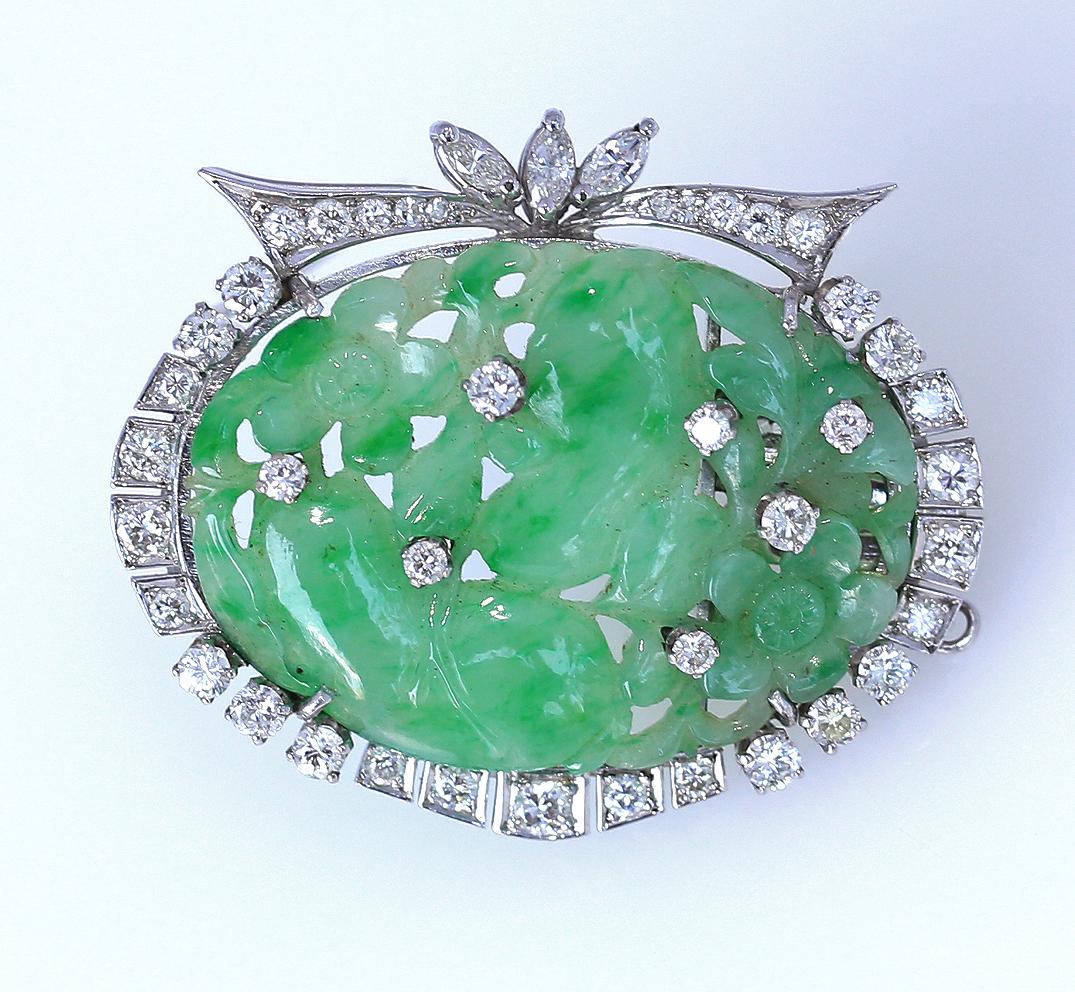 Fine Art Deco carved Jade Brooch with Floral motives. Diamonds are installed all around and also inside the Jade. Platinum cast. 

A pin on the backside ensures the brooch is tightly fixed. There is also a lock for the bracelet, it may have been
