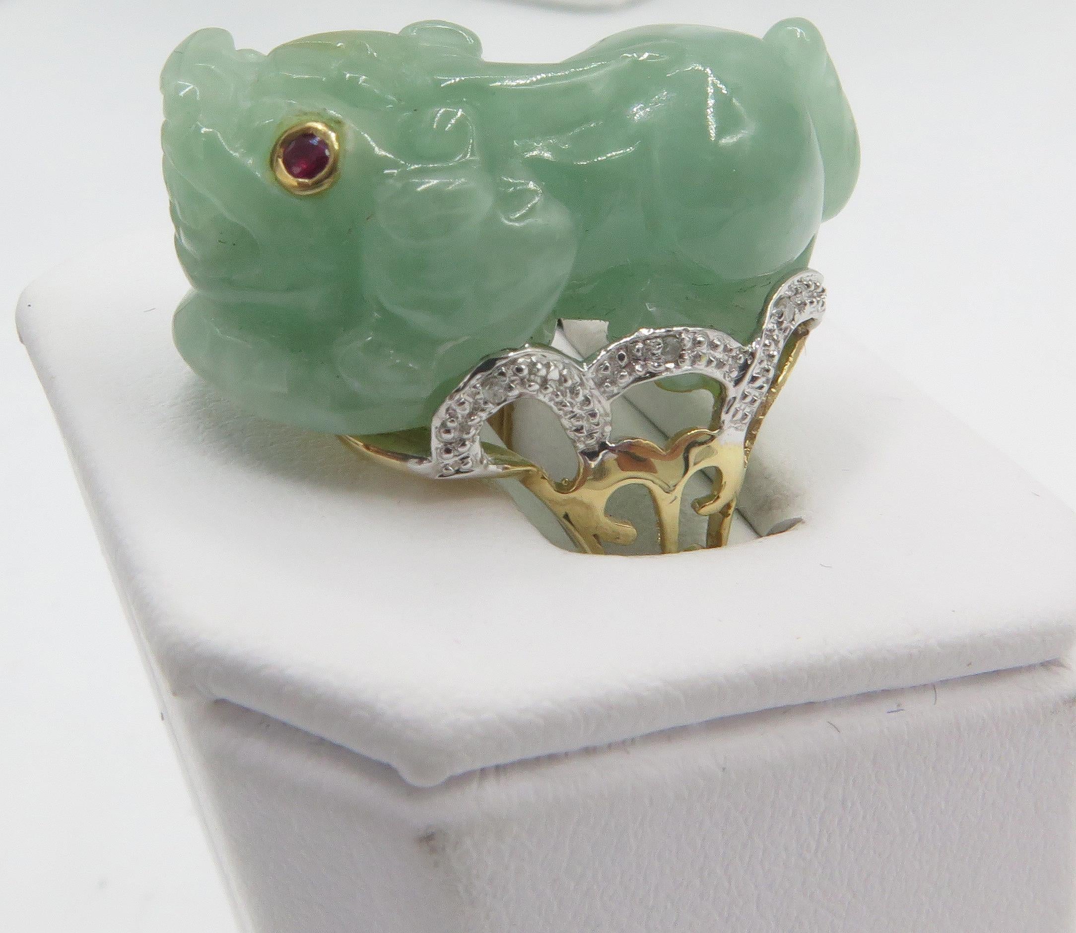 Beautifully carved jade foo dog with ruby eyes & diamond accented filigree shank. The, ring weighs 12.82 grams and it is a us ring size 7 1/2. The ring feature a beautiful mounting in 18k white gold with diamonds on the sides. The, beautifully