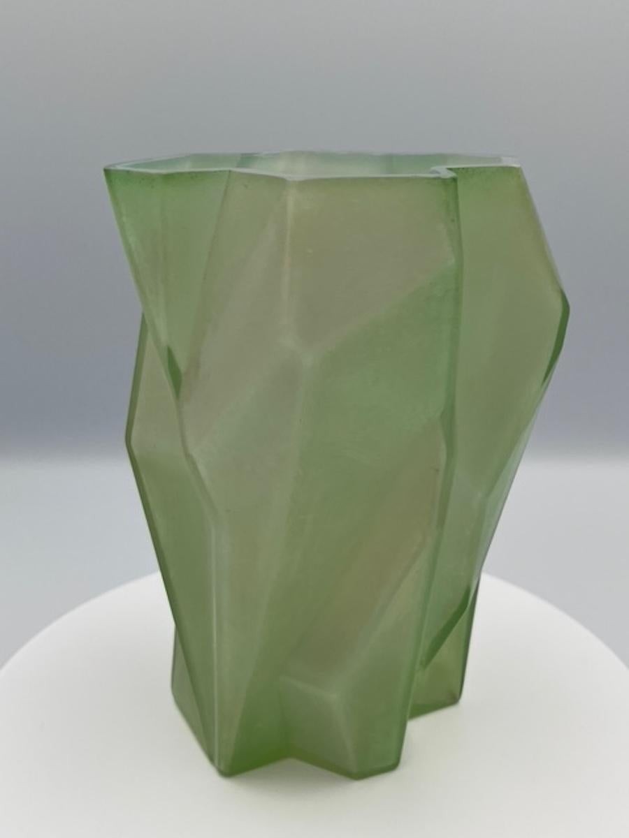 Il vaso Ruba Rombic, prodotto dalla Consolidated Glass Company, è un esempio iconico del design Art Deco. Realizzato in vetro incamiciato verde giada, questo splendido pezzo presenta audaci forme geometriche e motivi simmetrici, incarnando