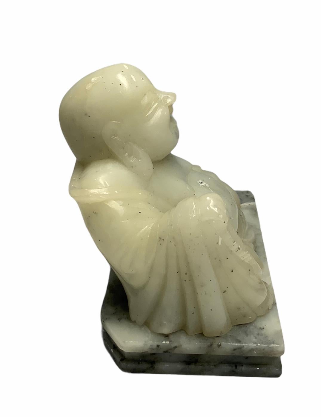 This is a carved Jade figure of a sitting Happy Buddha. He is sitting over a rectangular marble base.