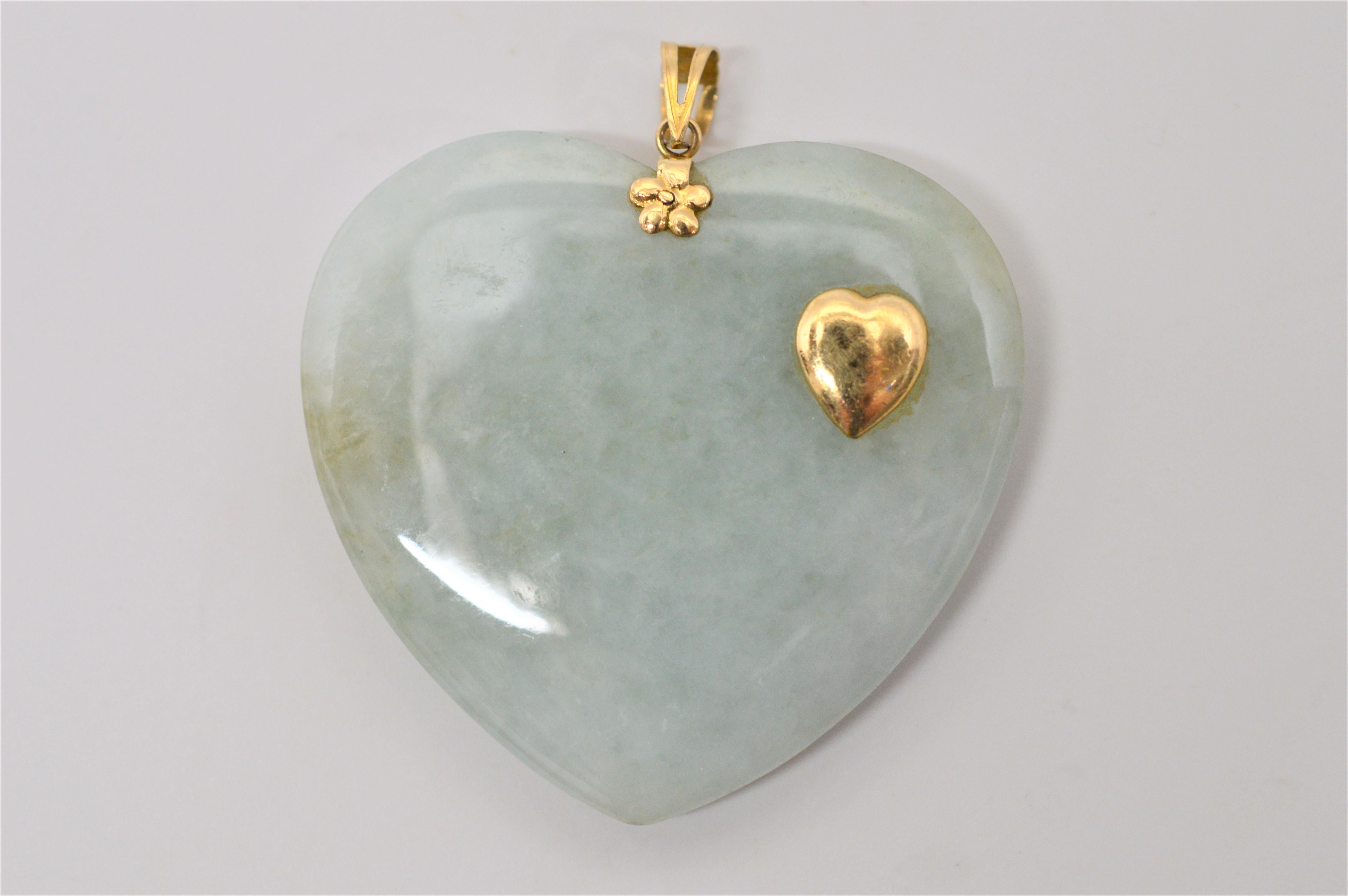 Fine and unusual, this Jade Heart  Pendant is made of beautiful natural white jade with soft green hues. Enhancing the serene piece is a small accent heart and decorative findings of 14 Karat Yellow Gold. The reverse side is polished and can also be