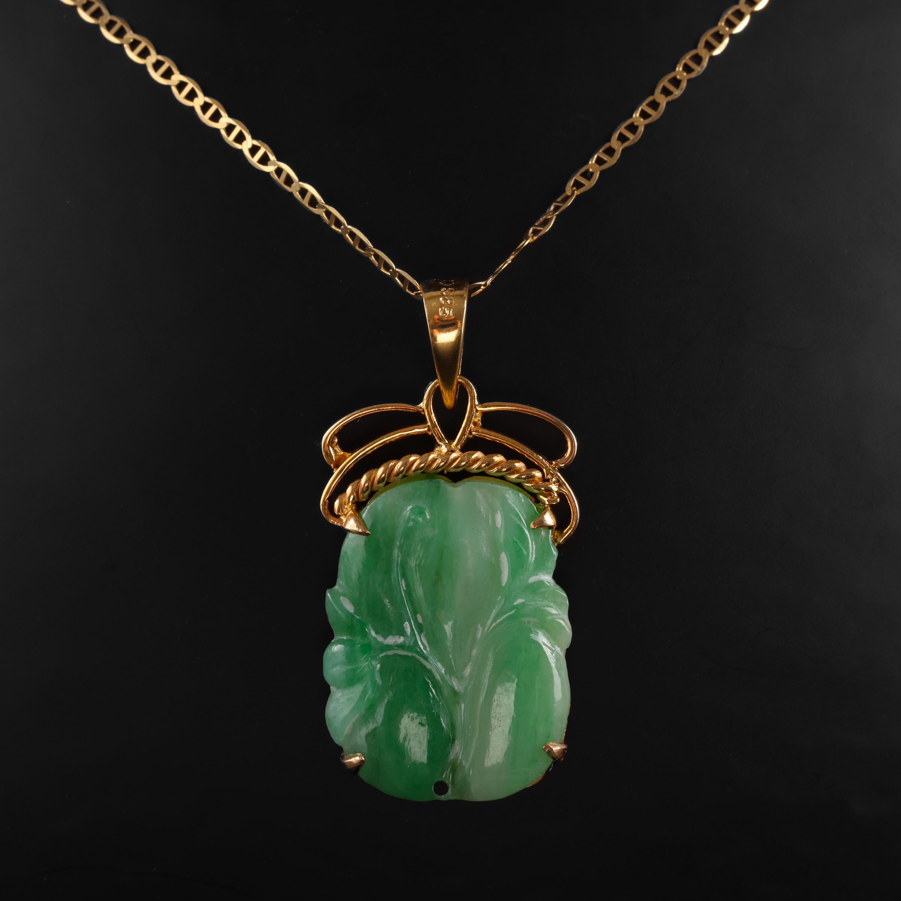 This 14K yellow gold pendant features an apple-green natural antique jade carving. The carving depicts what I believe to be a blossom; when held sideways. You see, there is a small hole in the very top and the very bottom of the jade carving and at