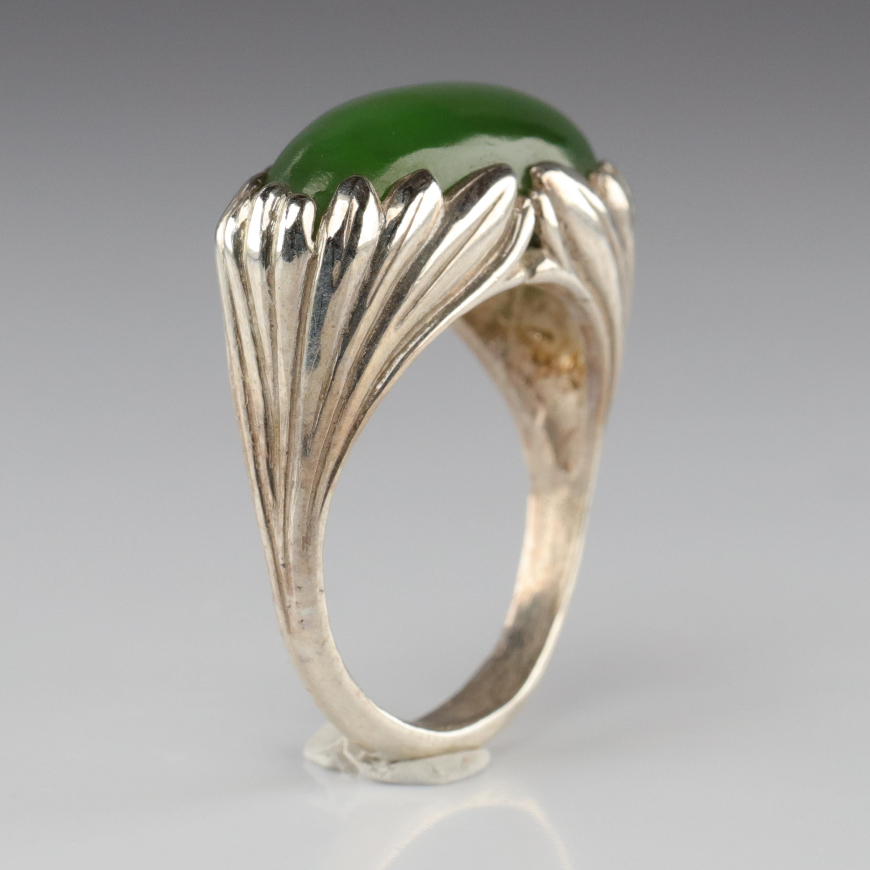 Not one but two artists created this ring. And it could be from the Art Nouveau era; the gorgeous symmetry of the carved silver clutching the summer-green jade cabochon, looking like something tucked beside a country stream. But this is not an