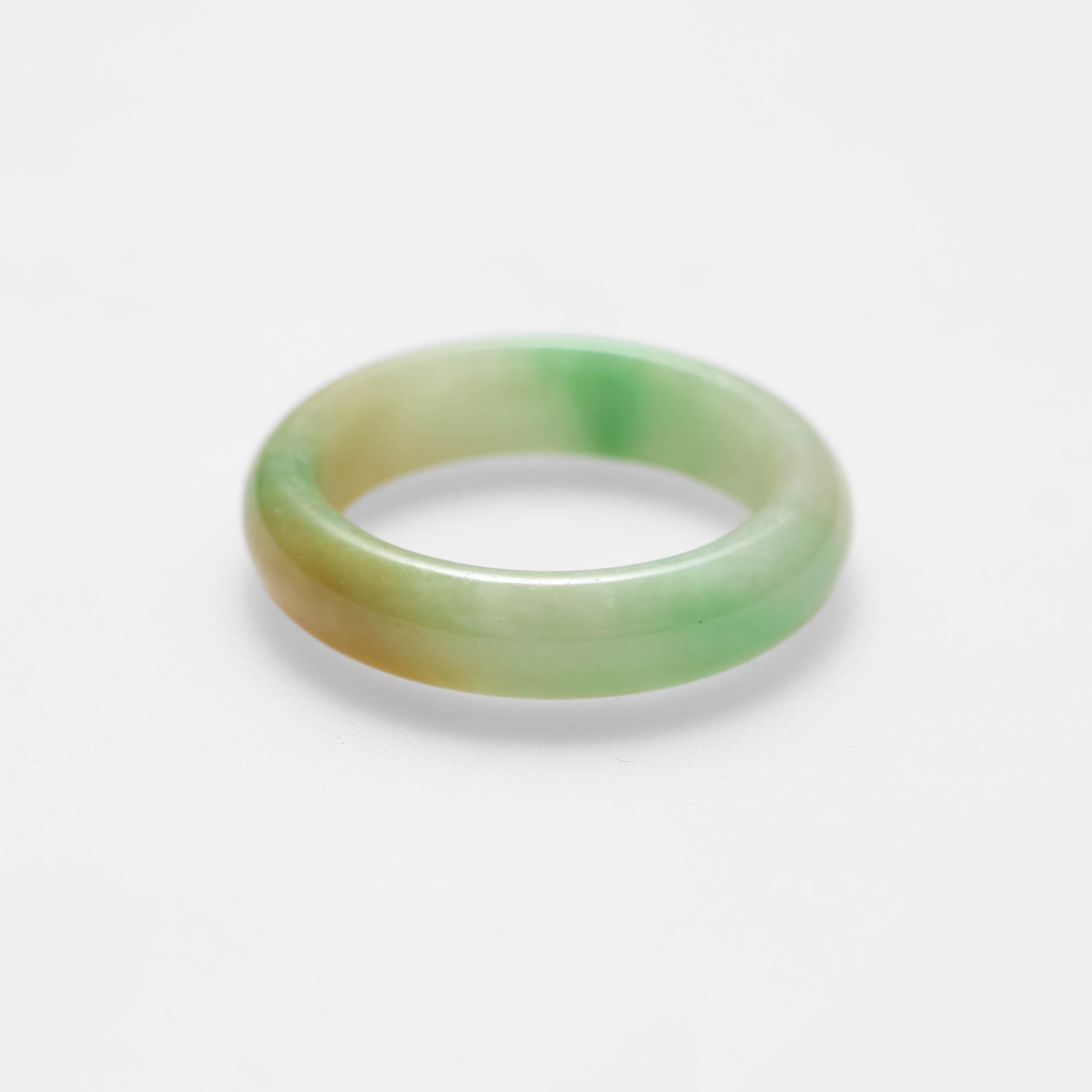 This ring was carved from a single piece of certified natural and untreated tricolor Burmese jadeite jade.  

This simple, elegant, and expertly carved jade band ring is highly translucent and features apple green, pale green and yellow jadeite