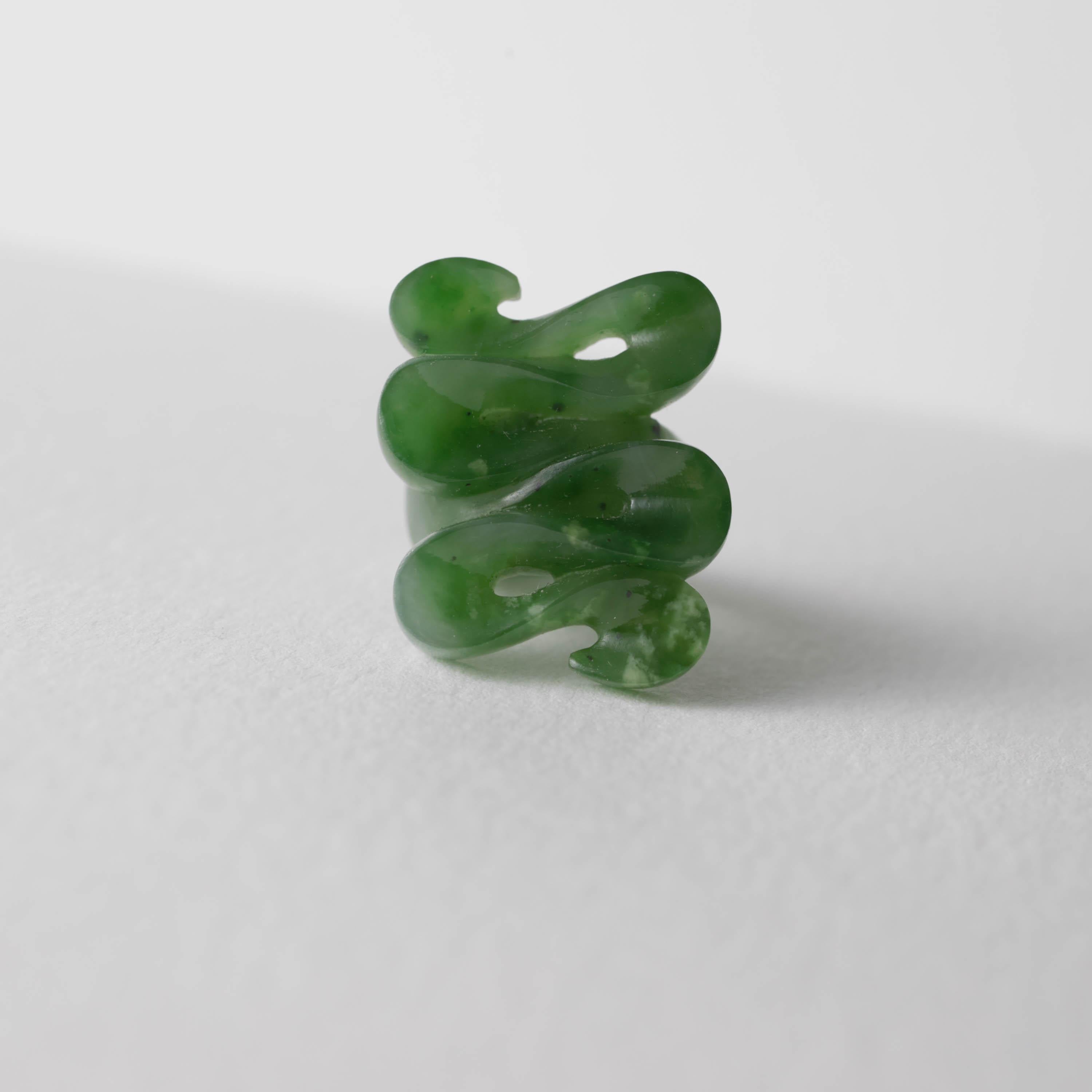 Carved from a single piece of translucent nephrite jade, this features an impeccably rendered waveform with a bright high polish. On the reverse, you will find a shank carved with a very soft matt finish. The juxtaposition of the glossy polish on