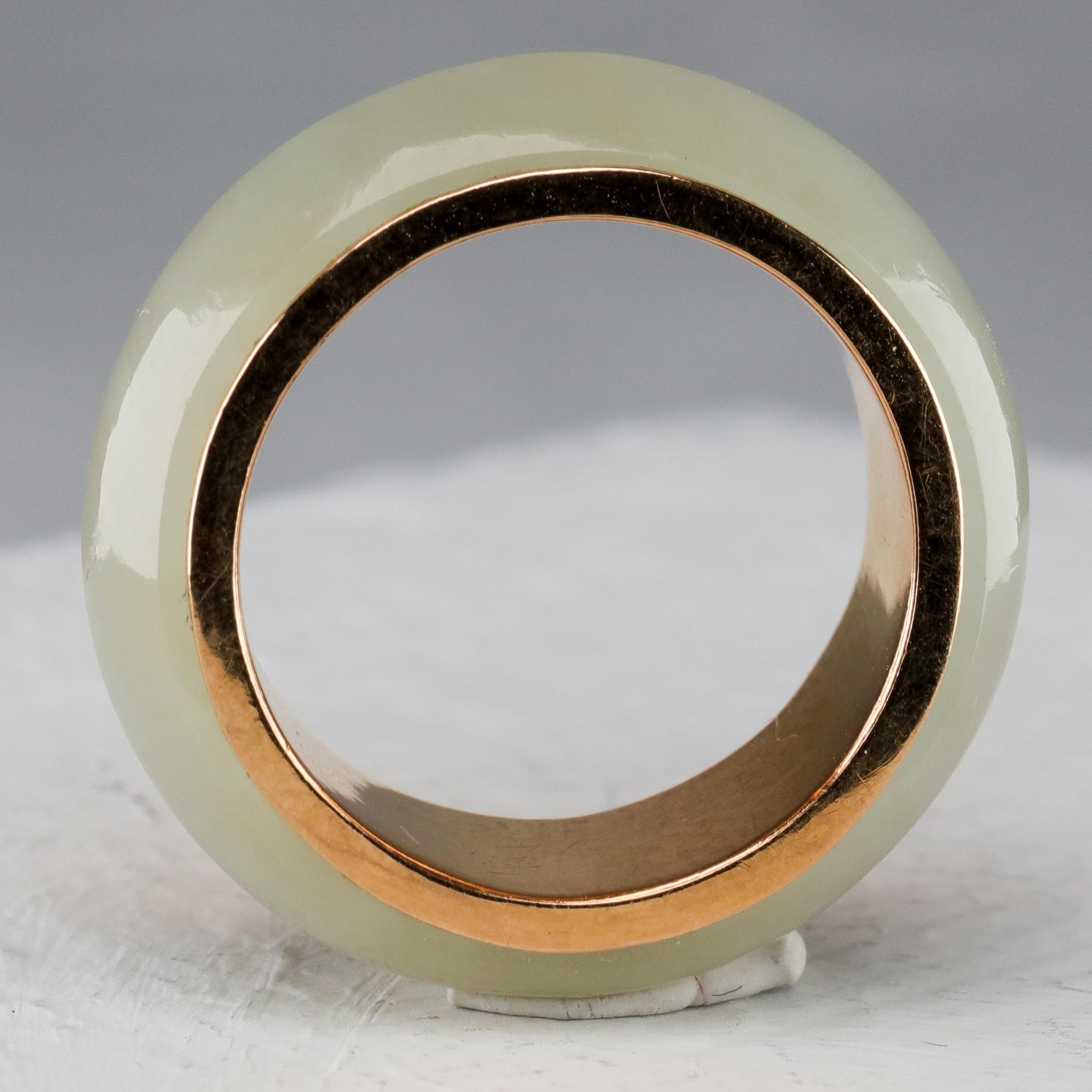 This is a high-quality jade and 14K yellow gold ring created in the 1970s. It features a hand-carved 100% natural and untreated (certified) nephrite jade ring in very pale green surrounding a solid 14K gold band. The jade has a luminous translucency