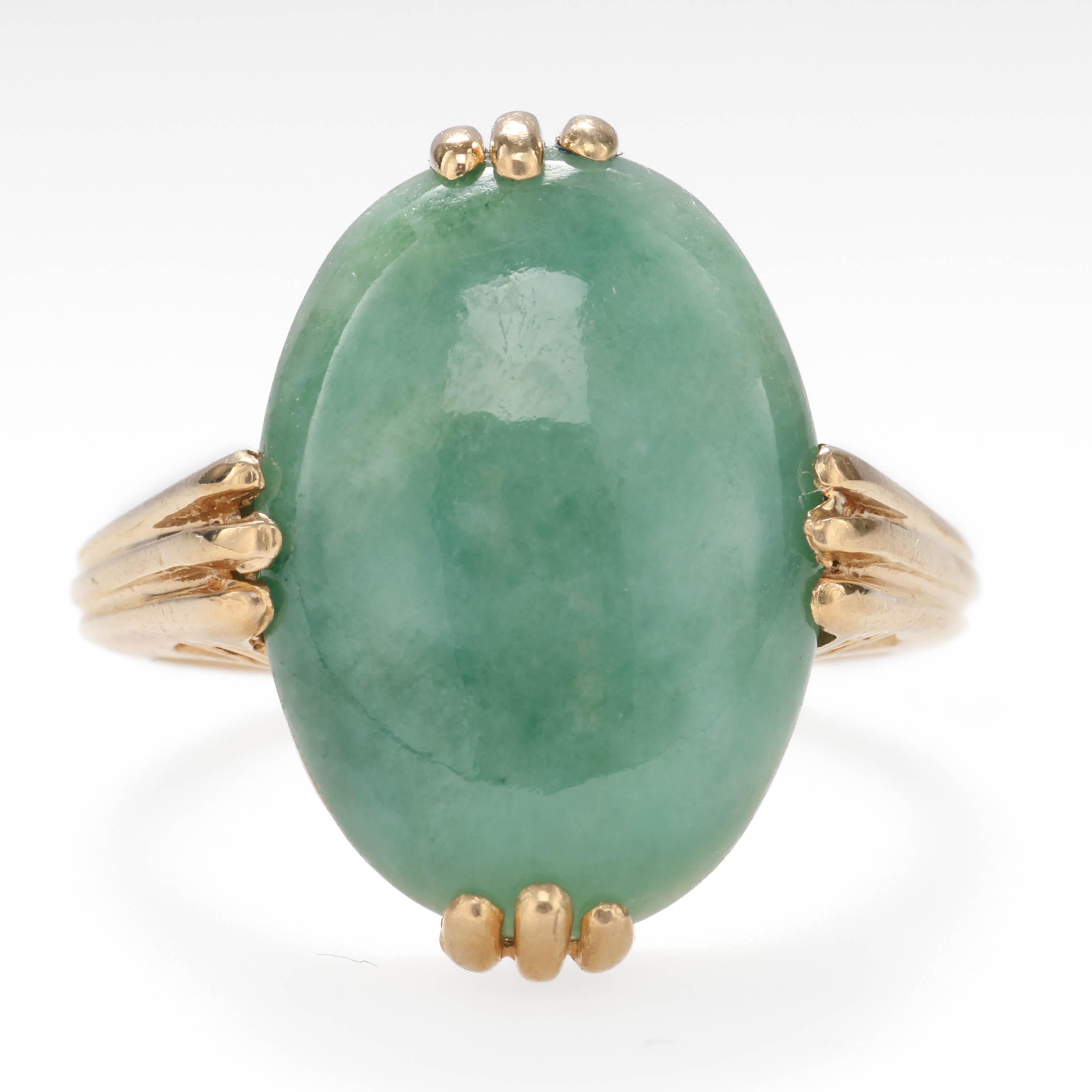 A bold oval cabochon of gorgeous sage green natural and untreated jadeite jade is gripped at all compass points by buttery 14k yellow gold in this Midcentury (circa 1960s) ring. 

The jade stone measures 16mm x 11.8mm x 3.88mm and the photos do an