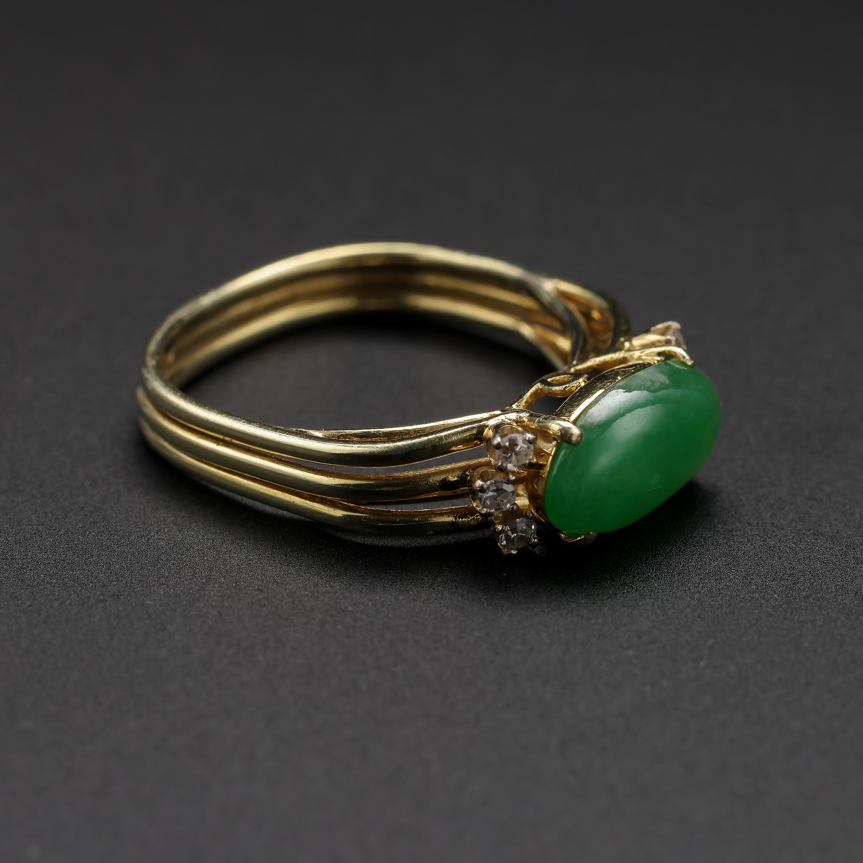 This vintage jade ring features an elongated 11.42mm x 6.55mm luscious green cabochon of translucent, certified-untreated jadeite. Three small but firey and bright near-colorless eye-clean diamonds are prong-set on either side of the jade and they