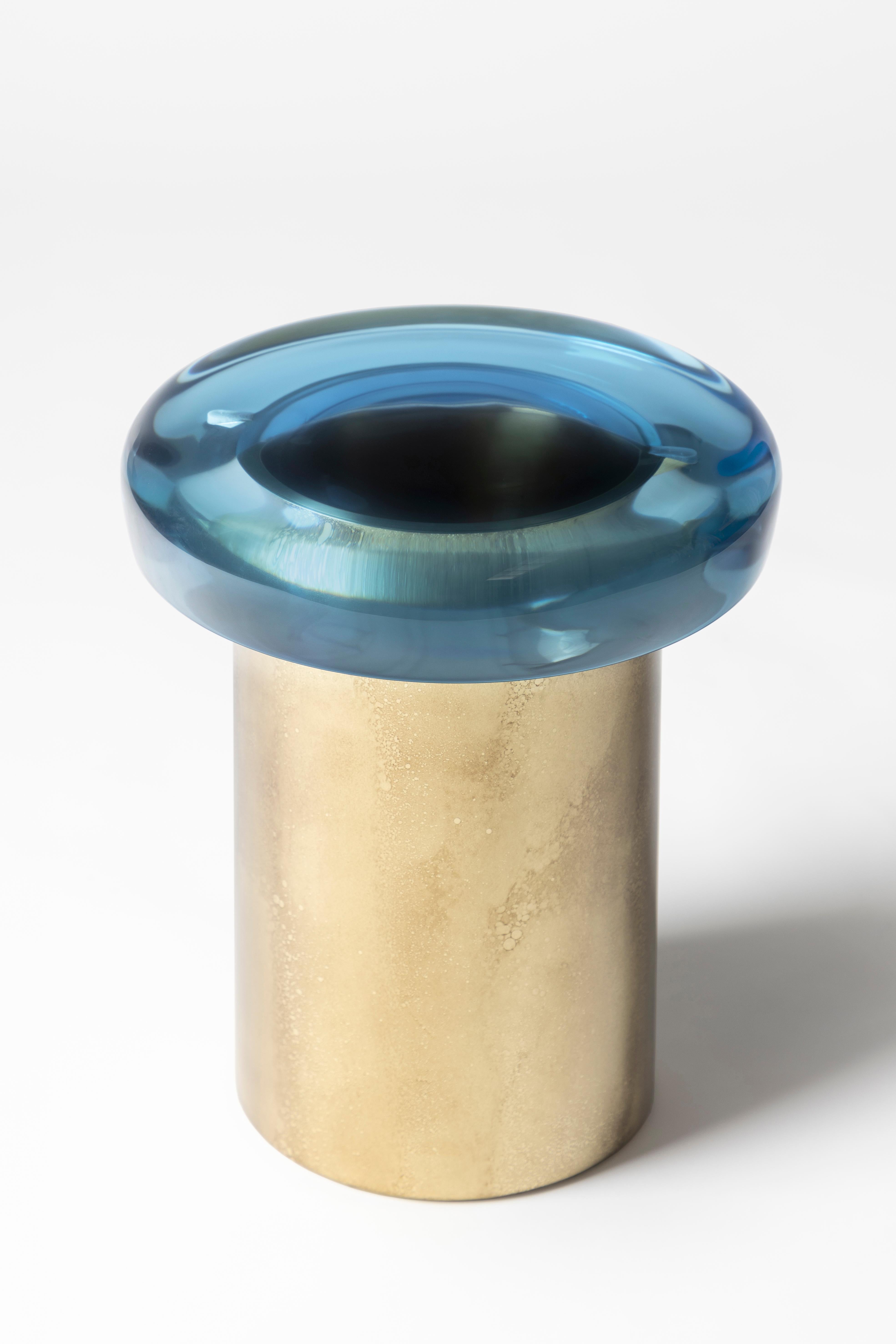 Le tabouret Nature se caractérise par une transparence éthérée et une surface réfléchissante qui joue naturellement avec la lumière. L'assise aux couleurs vives repose sur une base cylindrique en laiton, dont le veinage distinctif est obtenu grâce à