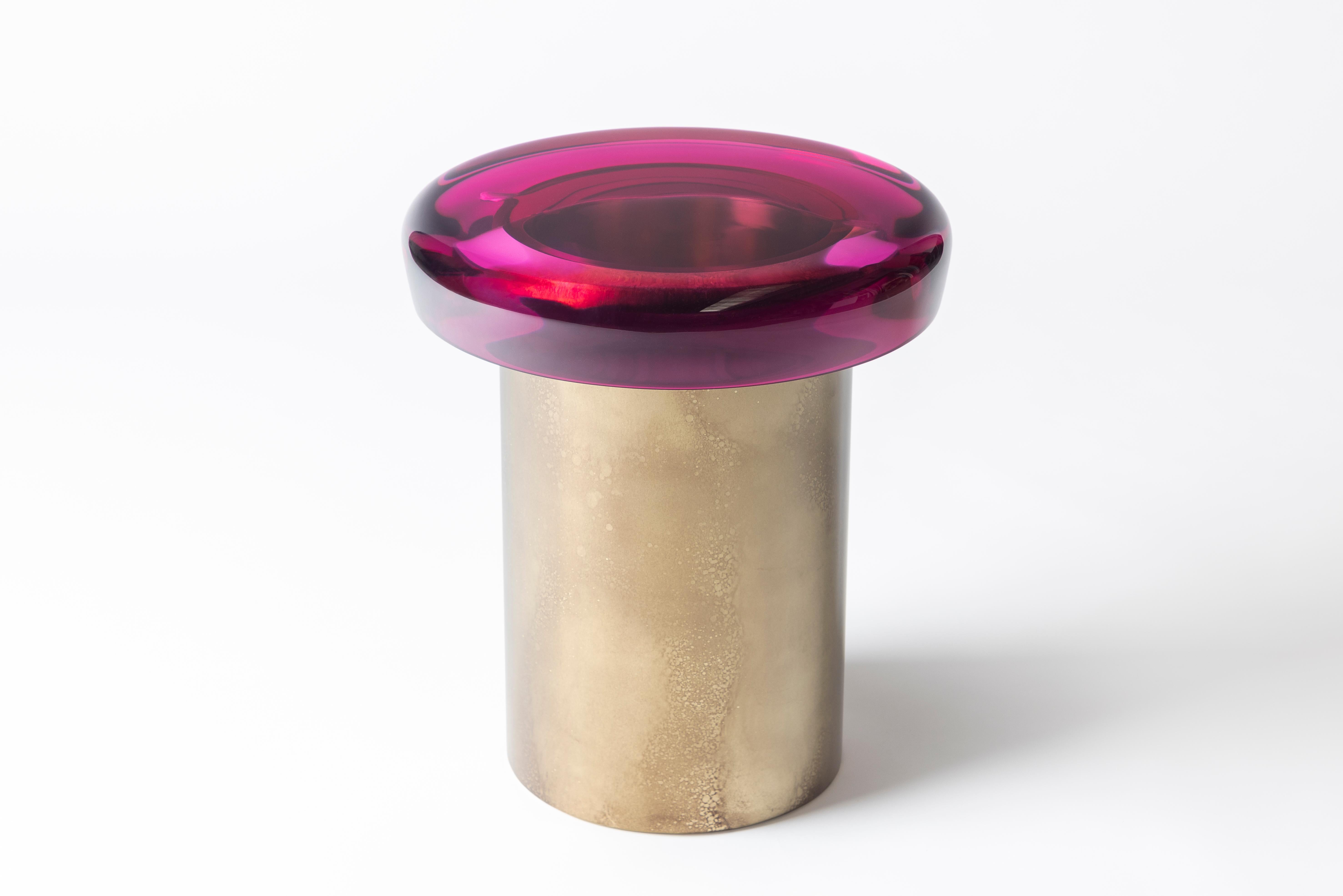 Le tabouret Nature se caractérise par une transparence éthérée et une surface réfléchissante qui joue naturellement avec la lumière. L'assise aux couleurs vives repose sur une base cylindrique en laiton, dont le veinage distinctif est obtenu grâce à