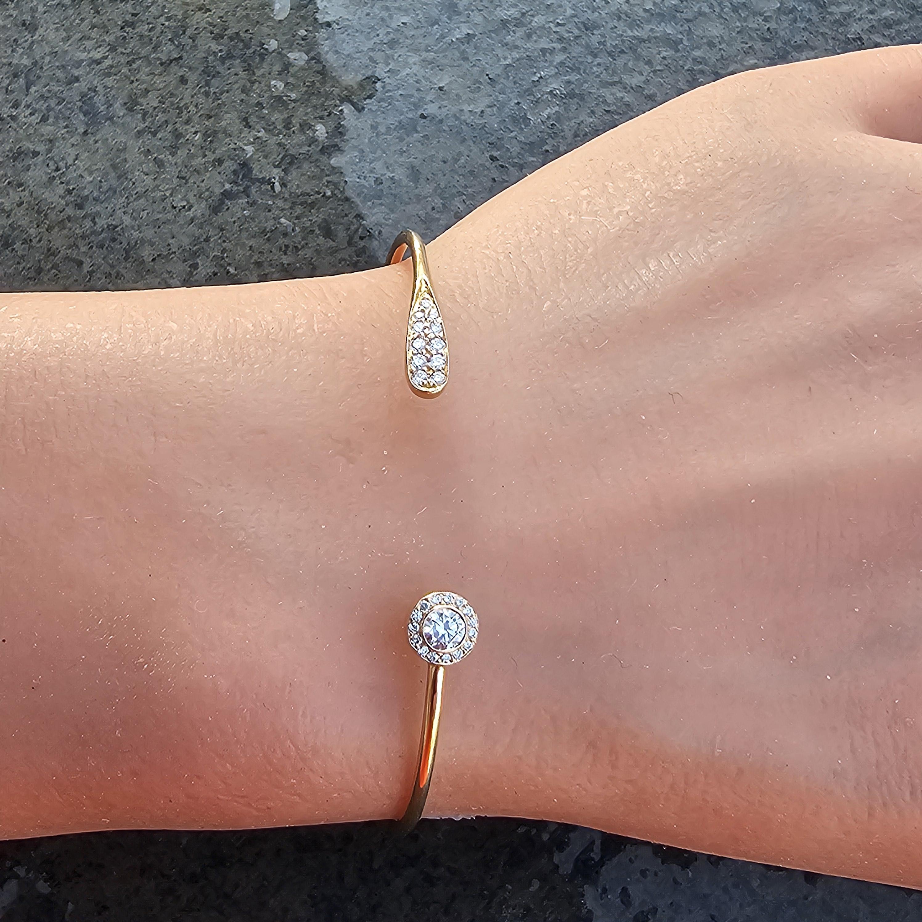 Here is a stunning Jade Trau cuff bracelet in 18k gold and rose gold, featuring a brilliant white diamond surrounded by small pave round diamonds, and then the other side has an elongated pave diamond end. This bracelet is so elegant and looks great