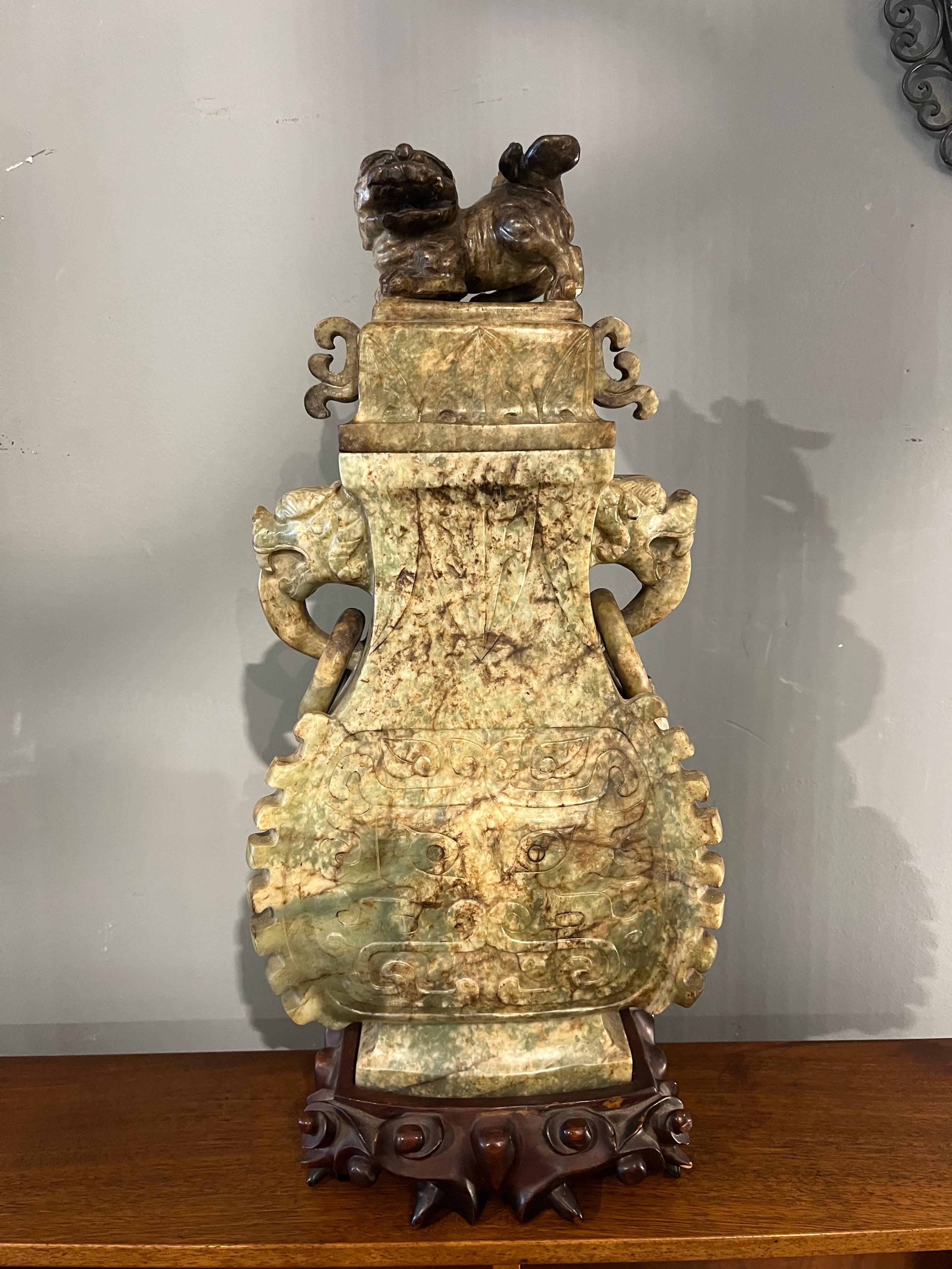 Jade Vase with Rings. China, Qing Dynasty, 19th century. A Chinese jade vase dating back to the 19th century, Qing Dynasty era. It is a refined art object, entirely carved in natural jade with warm green and brown hues, resting on a finely carved