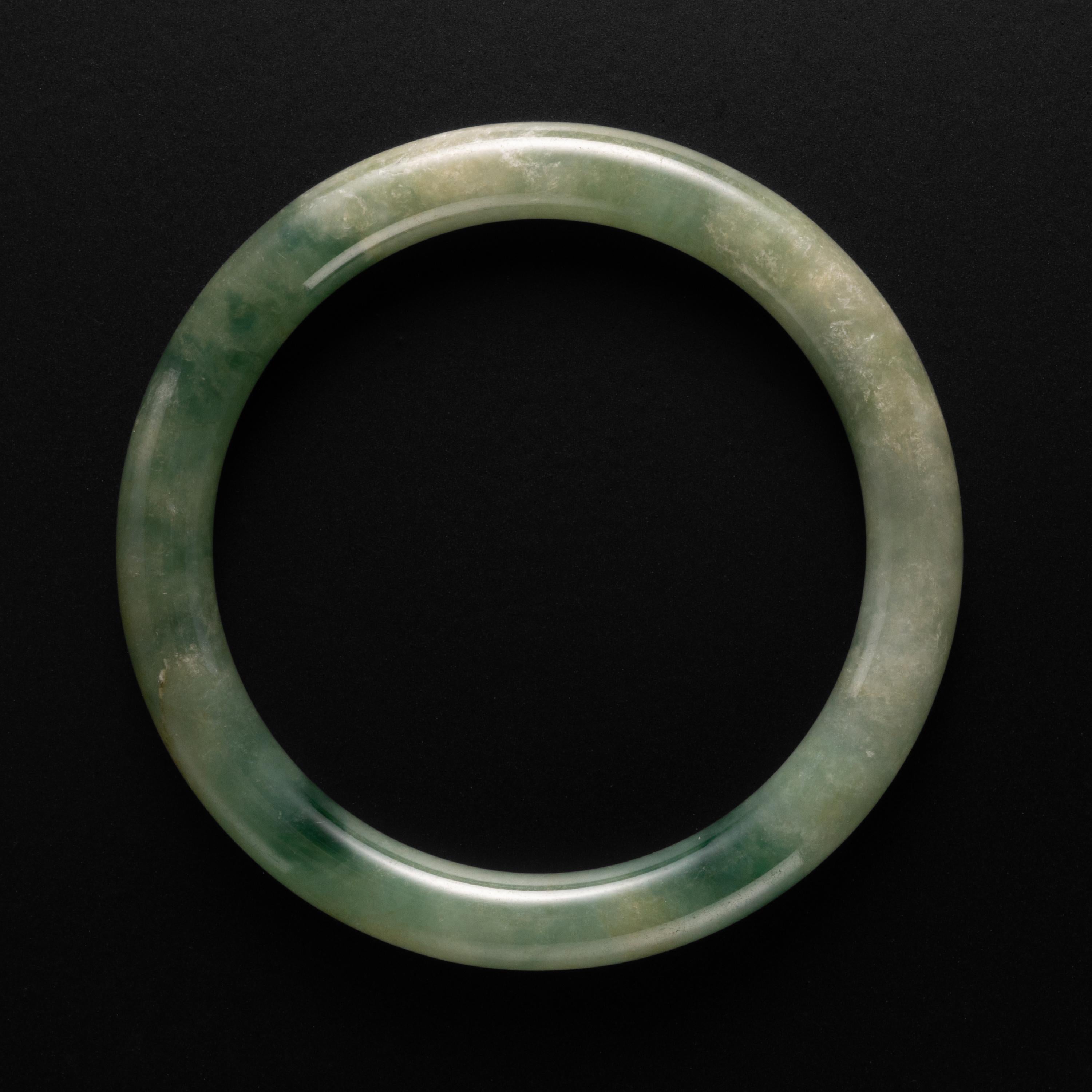 This is a small but utterly gorgeous highly translucent natural and untreated jadeite jade bangle. With an interior diameter of 54mm, this should fit over a smaller to average-sized wrist. 

The lush greens are visually refreshing and because the