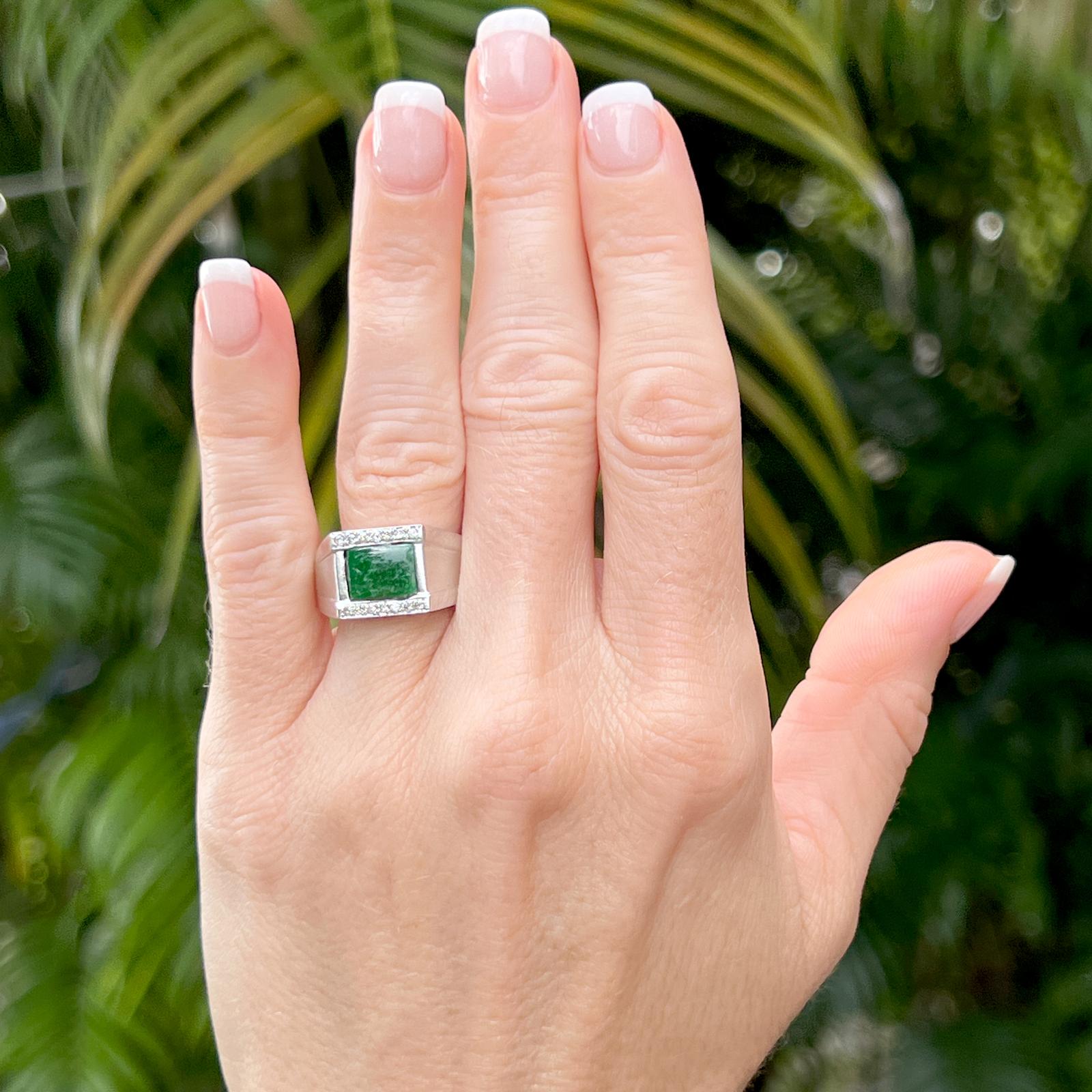 Ring aus Jadeit und Diamanten, gefertigt aus 14 Karat Weißgold. Der Ring besteht aus einem tiefgrünen Jadeit im Cabochon-Schliff und 14 runden Diamanten im Brillantschliff mit einem Gesamtgewicht von etwa 0,18 Karat. Die Diamanten sind von der Farbe