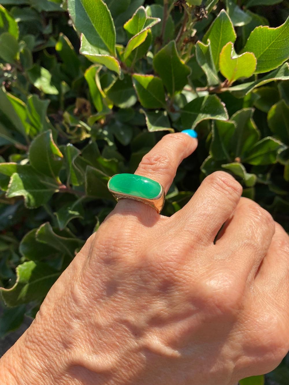 Jadeite Green Gold Ring Deep Color 9.30 x 24 mm Long Circa 1970's
14 karat yellow gold ring is set in a heavy, secure setting enclosed in gold. The shank measures 9-6mm at the rings back.
The Jade is a desirable color with deep transparency

The