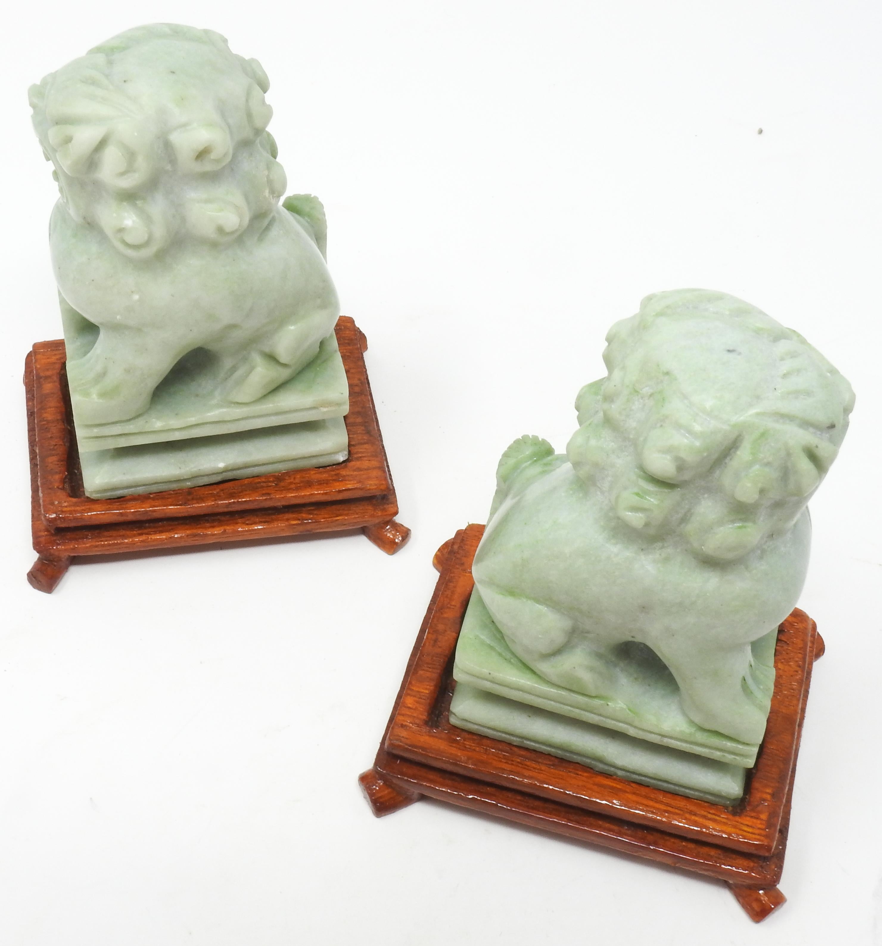 Offering this magnificent pair of Jadeite guardian foo dogs. They are a small simple pair done in the mid-20th century. The small wooden bases were hand carved. The foo dogs sit atop a plinth with simple lines and curves.