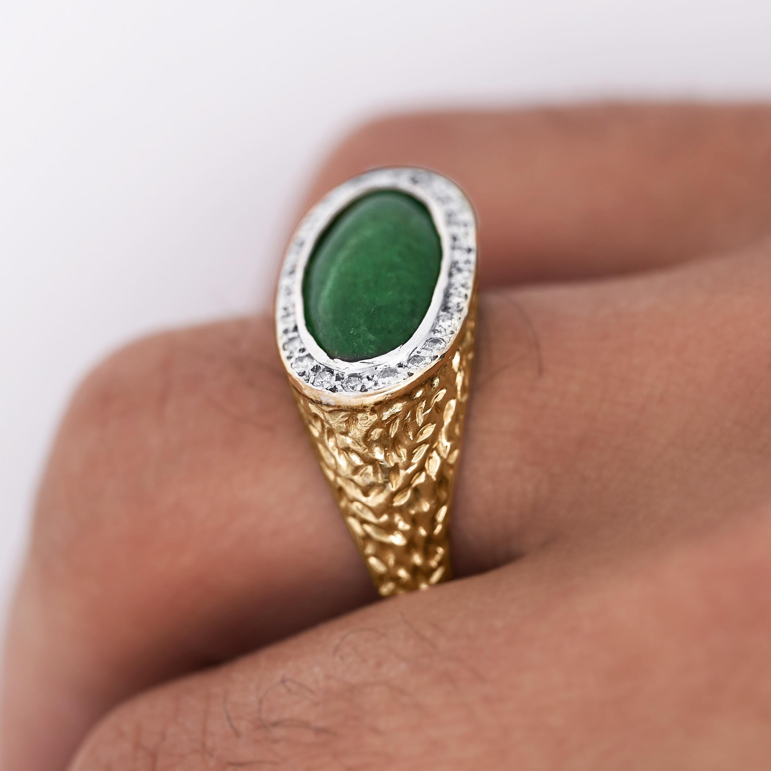 Herrenring aus natürlichem Jadeit im Ovalschliff, Typ A, gefasst in 14 Karat Gelb- und Weißgold mit Diamanten in Pavé-Fassung am Rand und Nugget-Struktur. Ring Größe 11, verstellbar.

Einzelheiten:
Artikel Typ: Herrenring
Metall: 14K Gelb- und