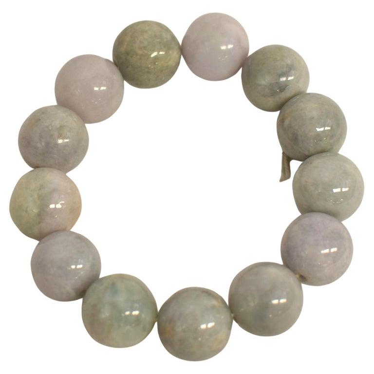 A stunning all-natural jadeite jade bracelet, featuring hefty approximately 18mm beads in a captivating mix of lavender, green, gray, and white hues. Each bead is uniquely colored by nature, offering a beautiful and harmonious blend that showcases