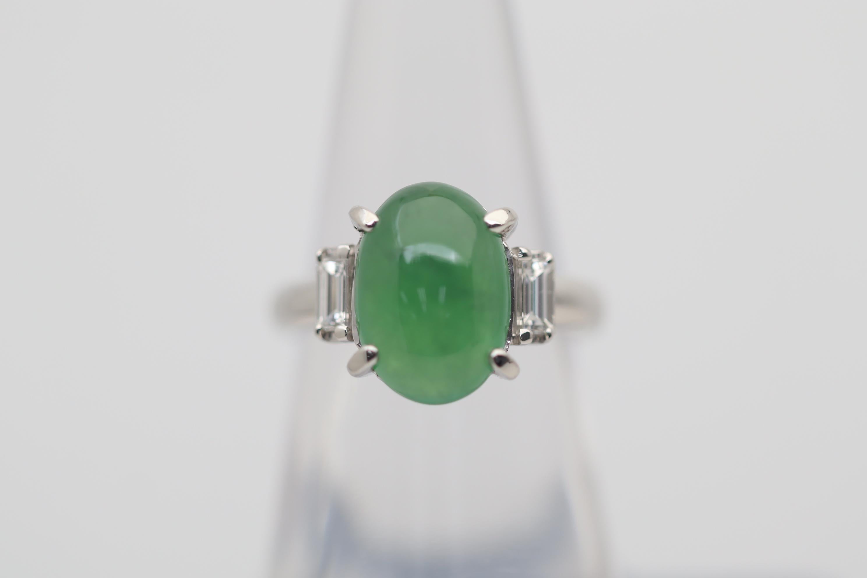 A classic 3 stone ring featuring a fine piece of natural jadeite jade. It weighs 4.71 carats and has a rich green color along with great translucency making the stone glow in the light. It is complemented by 2 baguette diamonds set on its sides and