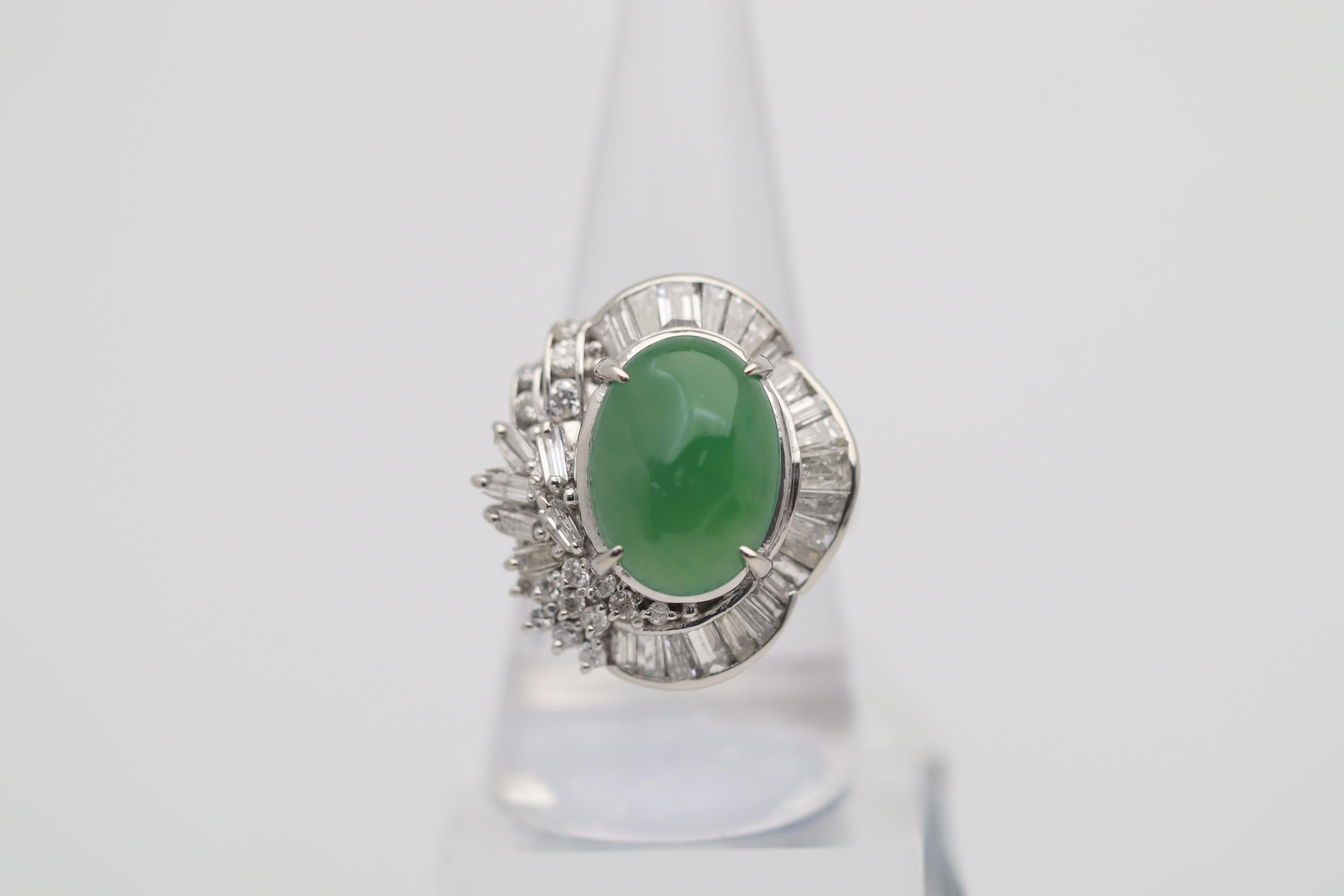 A lovely platinum made cocktail ring featuring a natural jadeite jade weighing 7.83 carats. It has a soft, even green color with excellent luster as light rolls across its surface. It is complemented by a cluster of baguette and round brilliant-cut